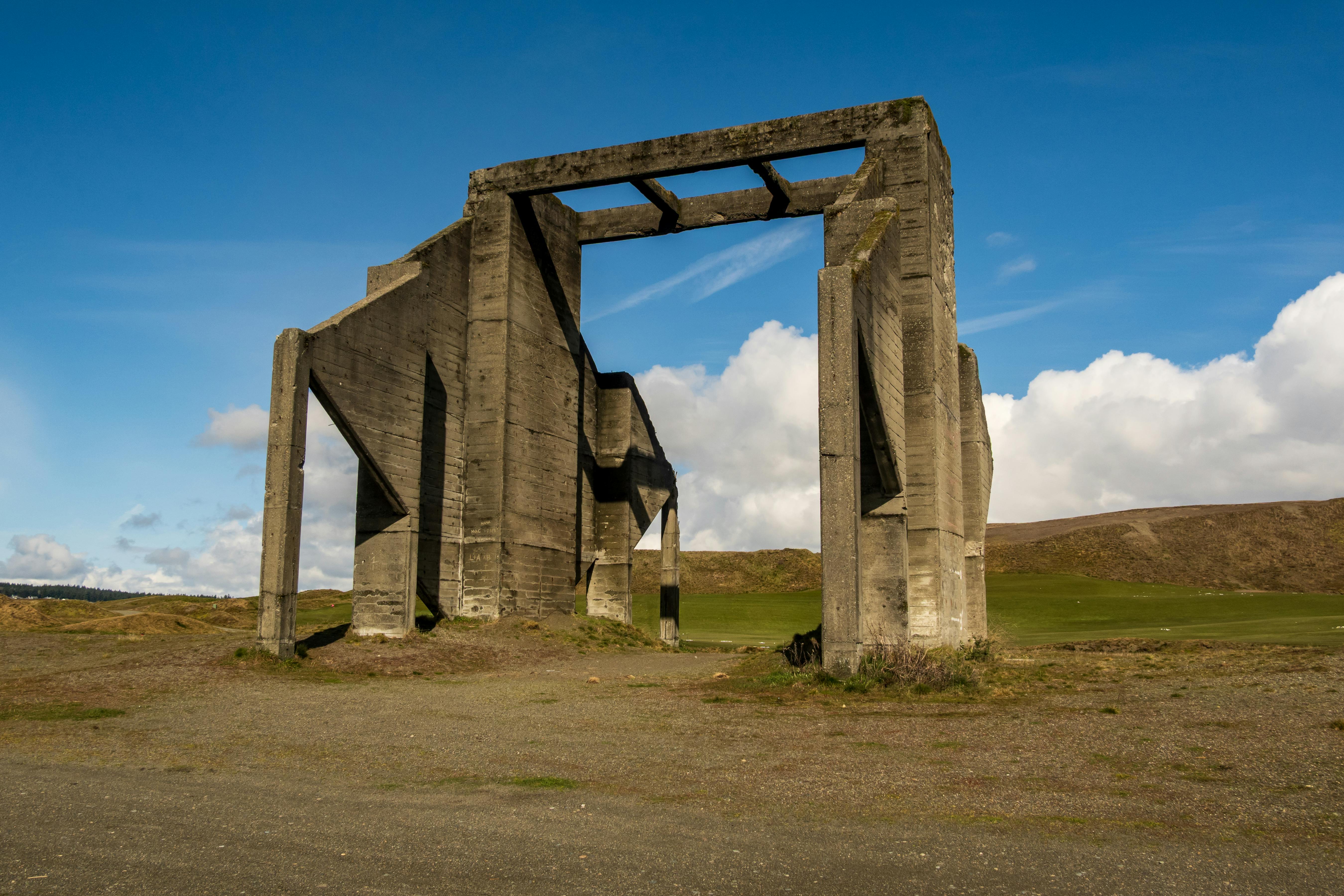 무료 탁 트인 시골 풍경 속, 맑고 푸른 하늘을 배경으로 인상적인 콘크리트 구조물이 우뚝 솟아 있다. 스톡 사진