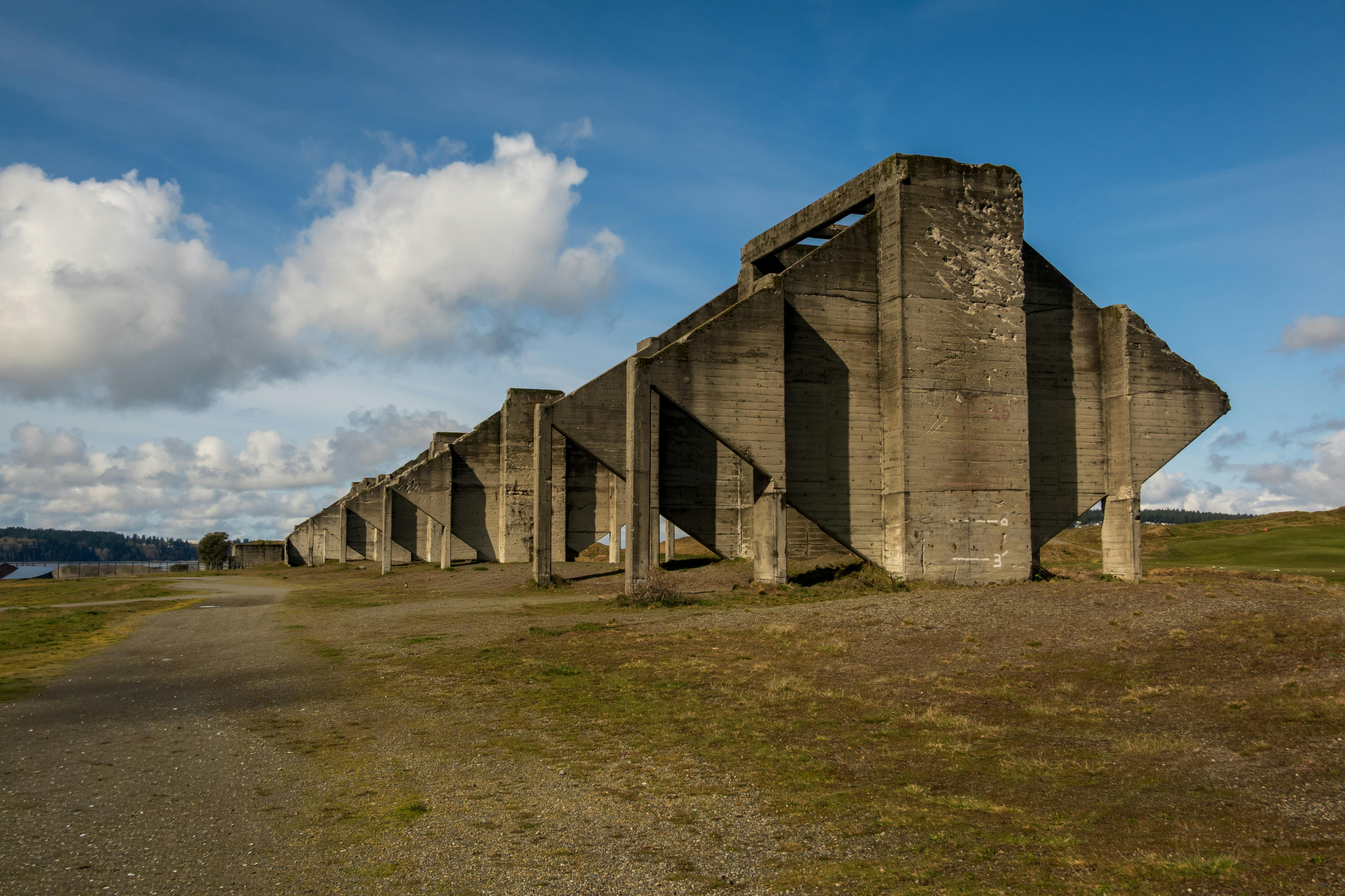 Kostnadsfria Gammal betongruin i ett öppet fält under en blå himmel med moln. Stock foto