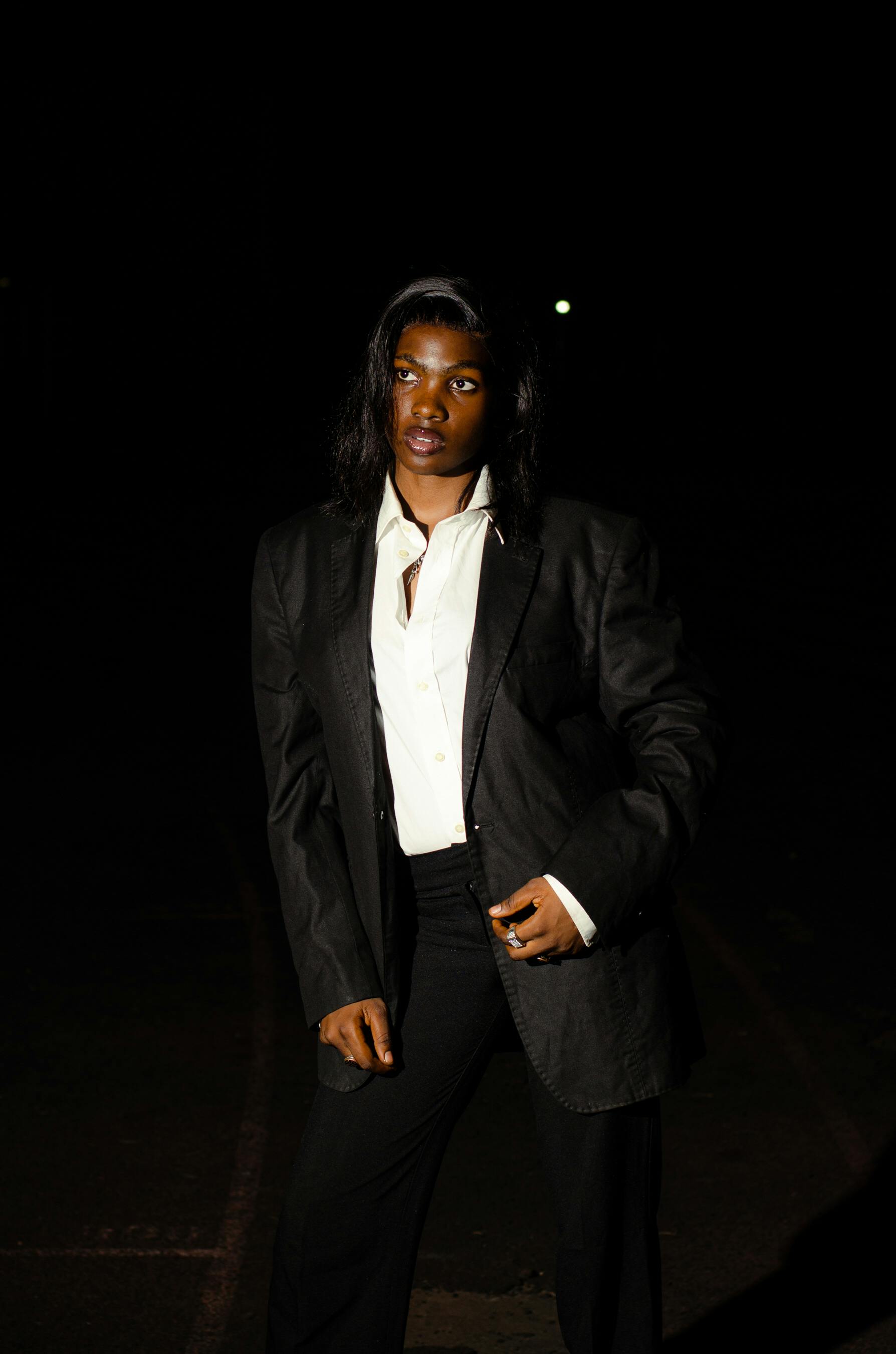 Безкоштовне Портрет впевненої людини у офіційному одязі під нічним освітленням, що підкреслює елегантність та витонченість. стокове фото