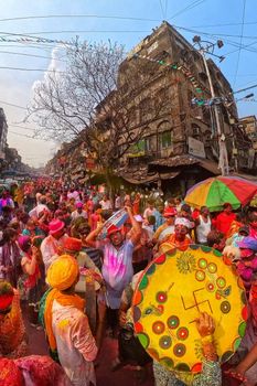 A lively Holi festival scene in Kolkata with people covered in colorful powders.