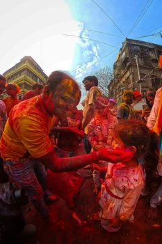 Colorful Holi festival scene with people enjoying traditional celebrations in Kolkata, India.
