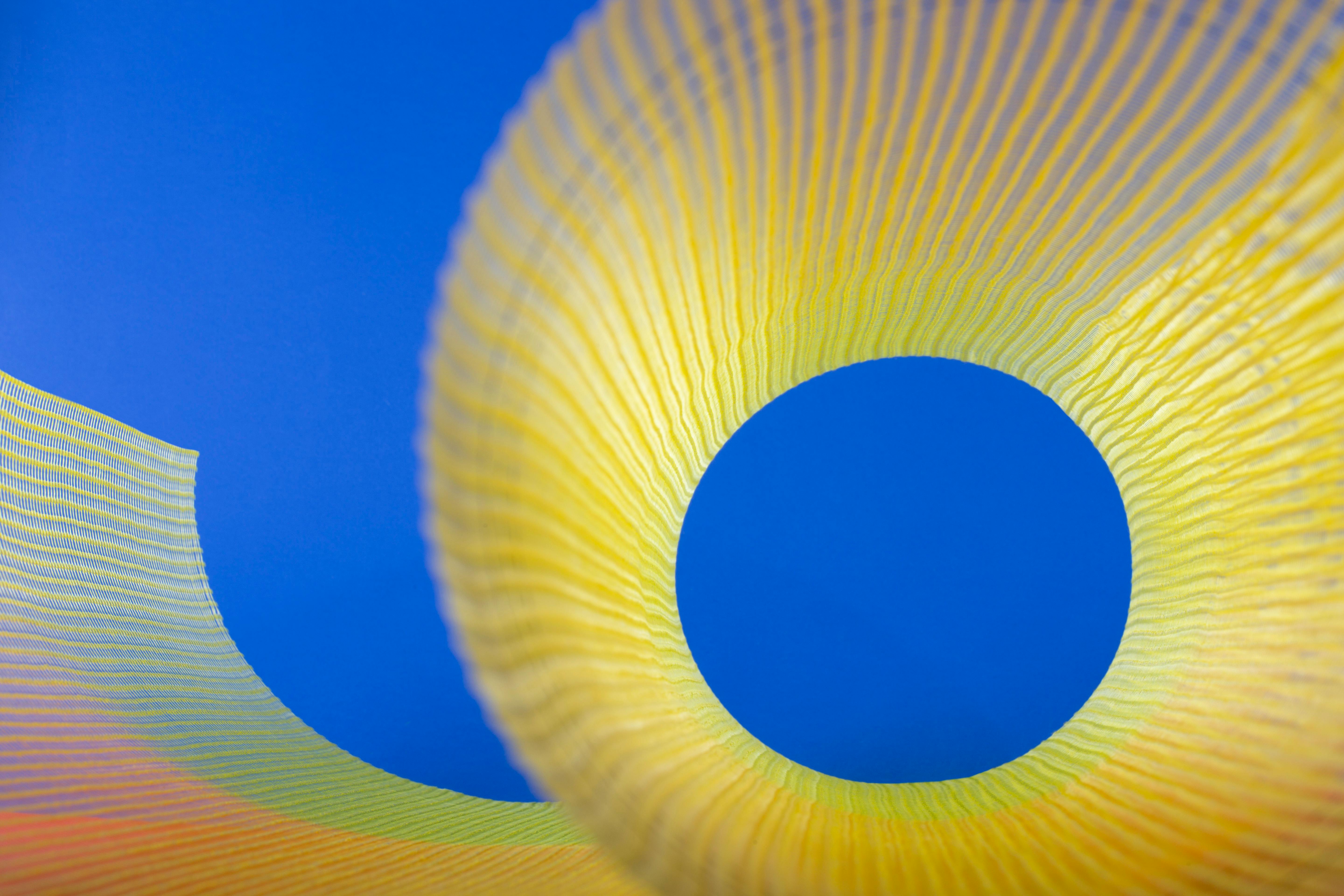 免费 充满活力的抽象图像，鲜艳的黄色螺旋在明亮的蓝色背景上形成鲜明对比，营造出生动的视觉效果。 素材图片