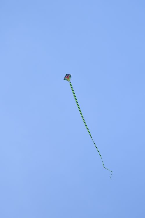 Free Vibrant kite soaring high, creating a striking contrast against a clear blue sky. Stock Photo