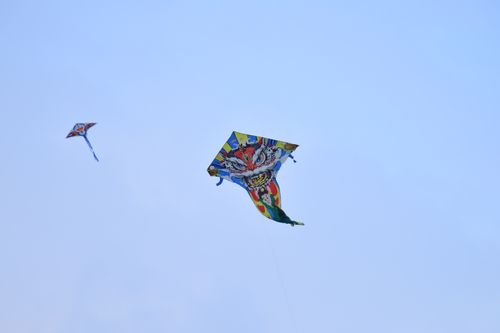 Free Vibrant kites soar in a clear blue sky, symbolizing freedom and joy in a serene outdoor setting. Stock Photo