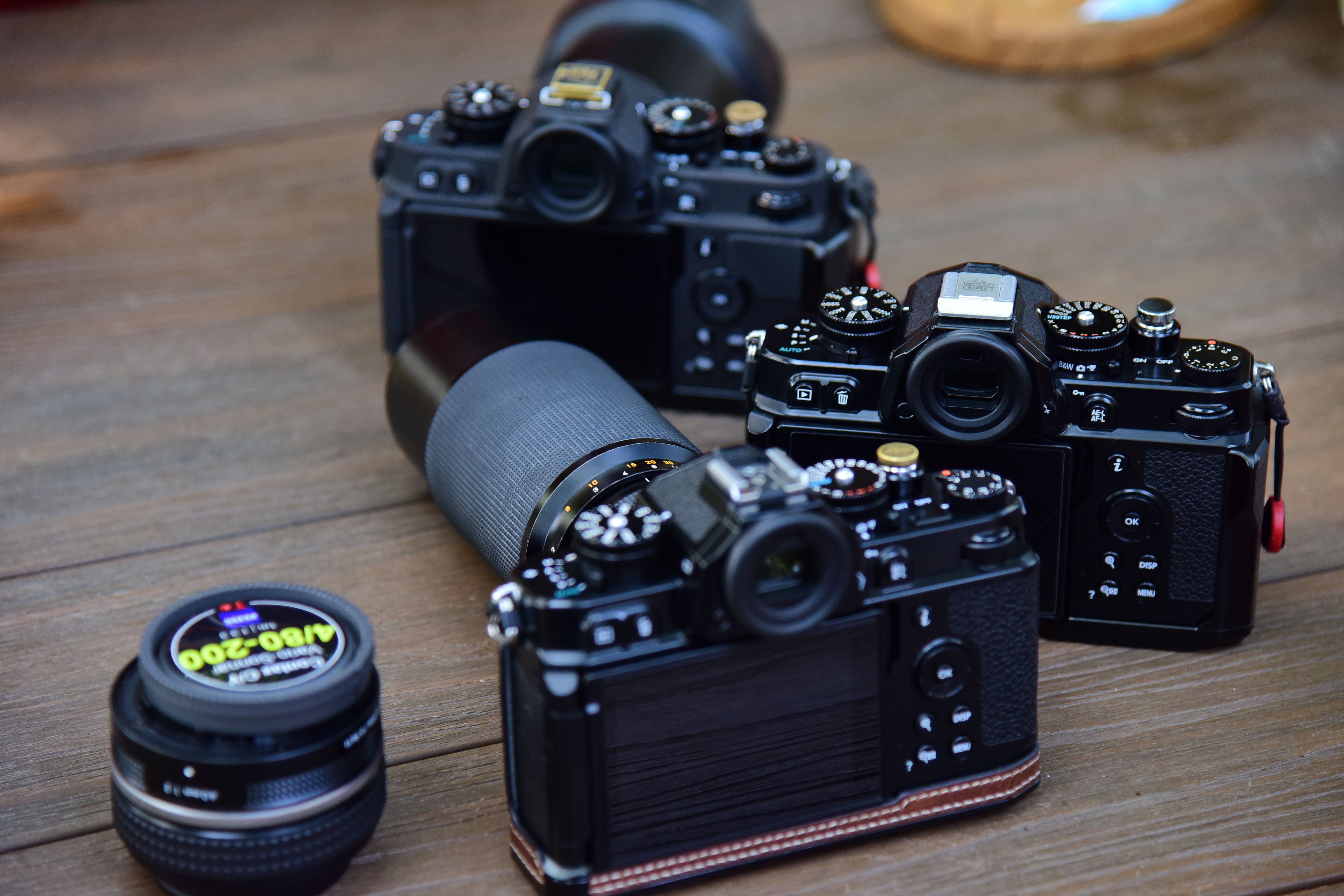 Multiple vintage-style cameras and lens displayed on a wooden table, ideal for photography enthusiasts.