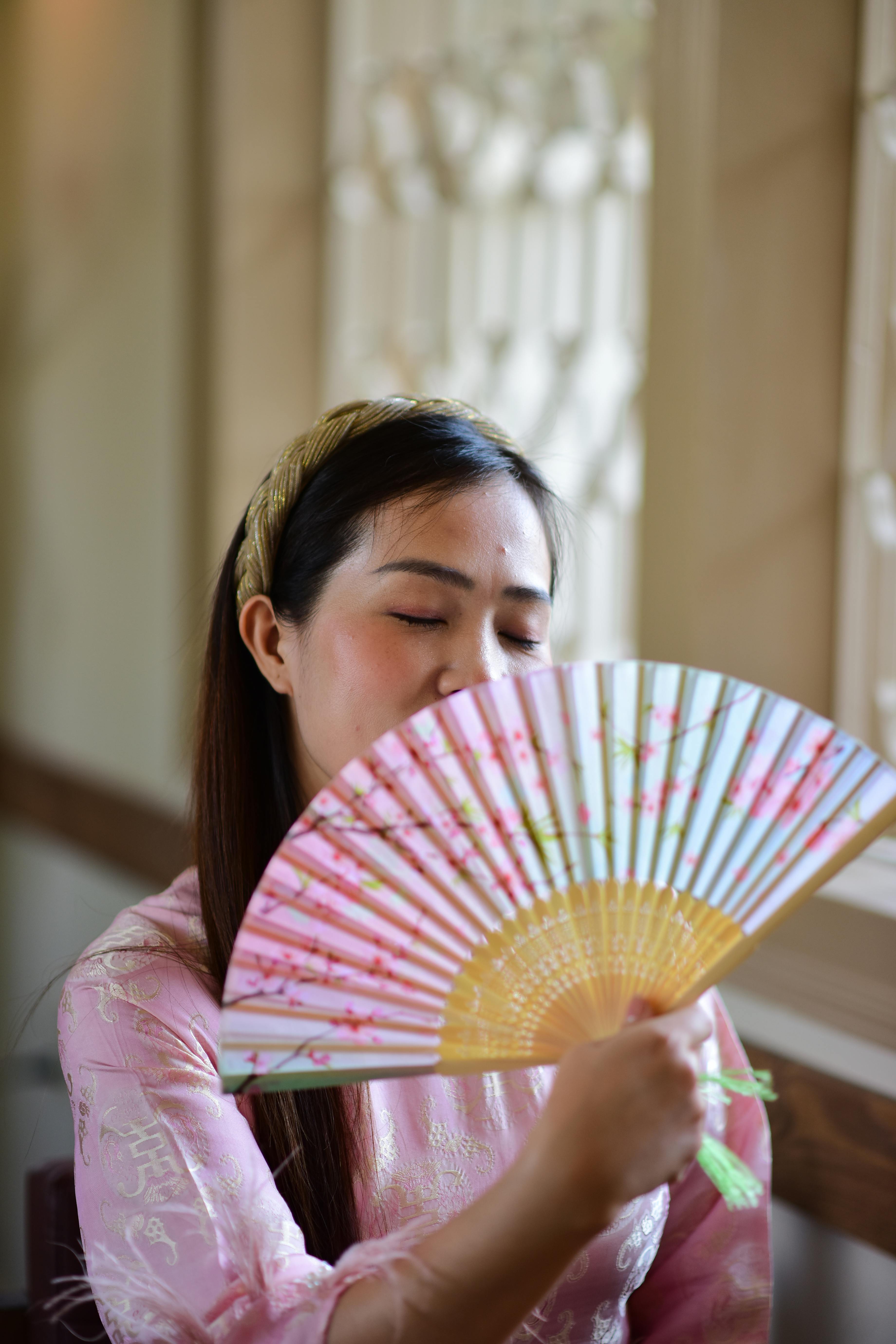 免费 一位身着传统服饰的年轻女子用扇子扇风，增添了优雅和风度。 素材图片