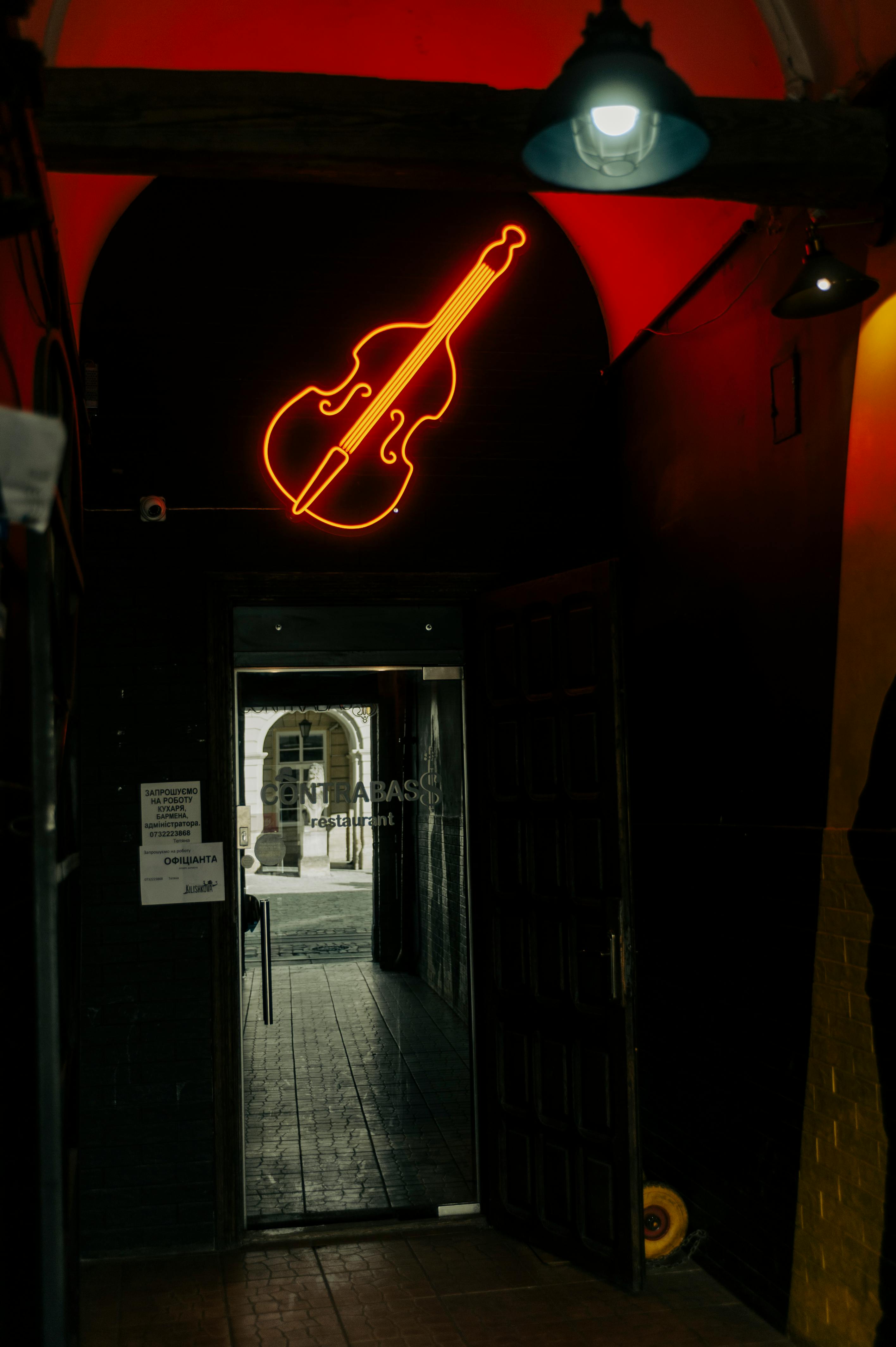 ingyenes Egy világító hegedűtábla jelzi egy zenei helyszín bejáratát Lvivben, Ukrajnában. Stockfotó