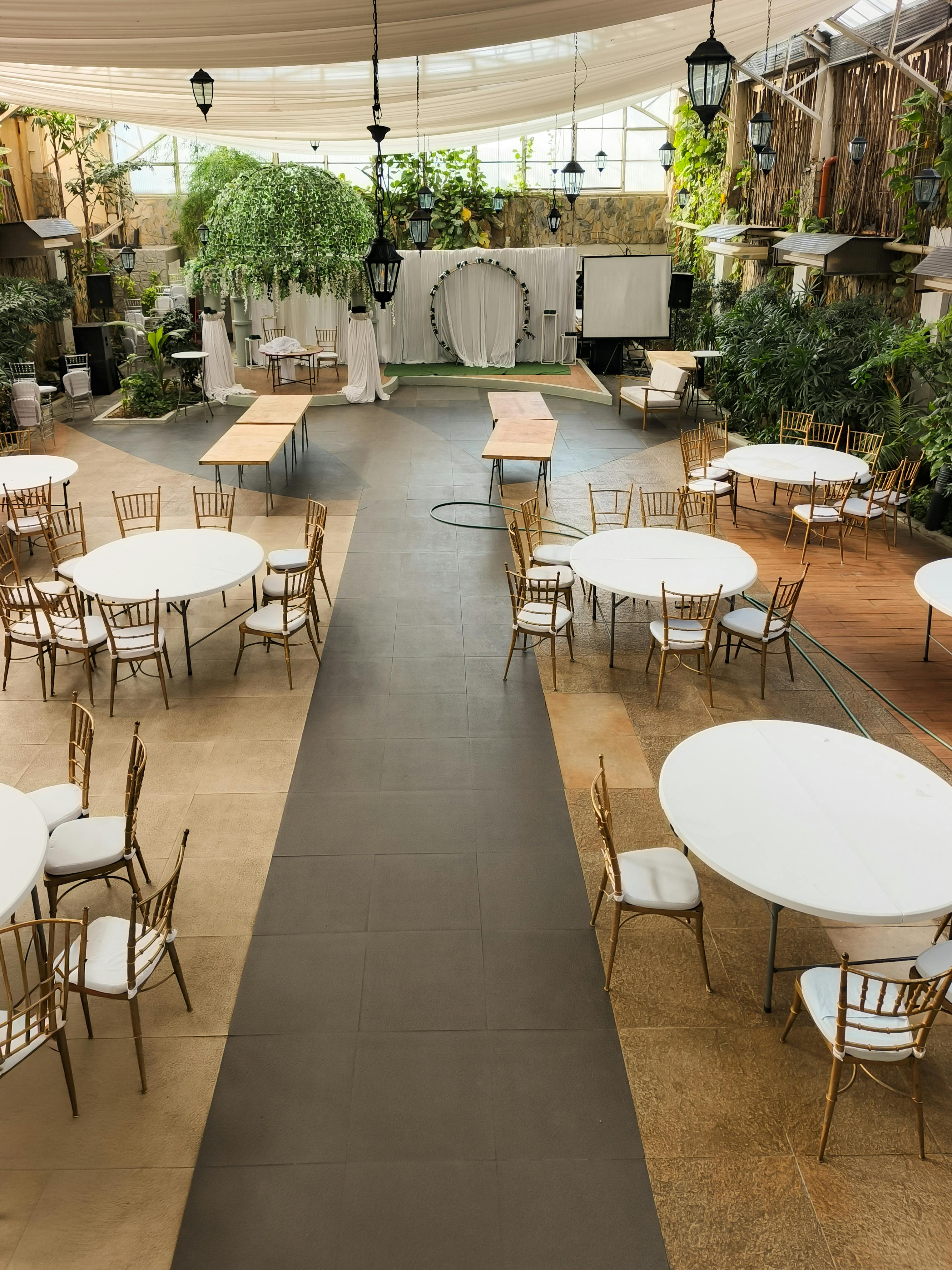 бесплатная Просторный зал для мероприятий с расставленными столами и стульями, обеспечивающий достаточное естественное освещение. Стоковое фото