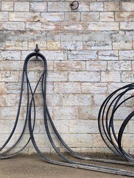 Curved steel cables elegantly draped against a textured stone wall, creating an industrial art scene.