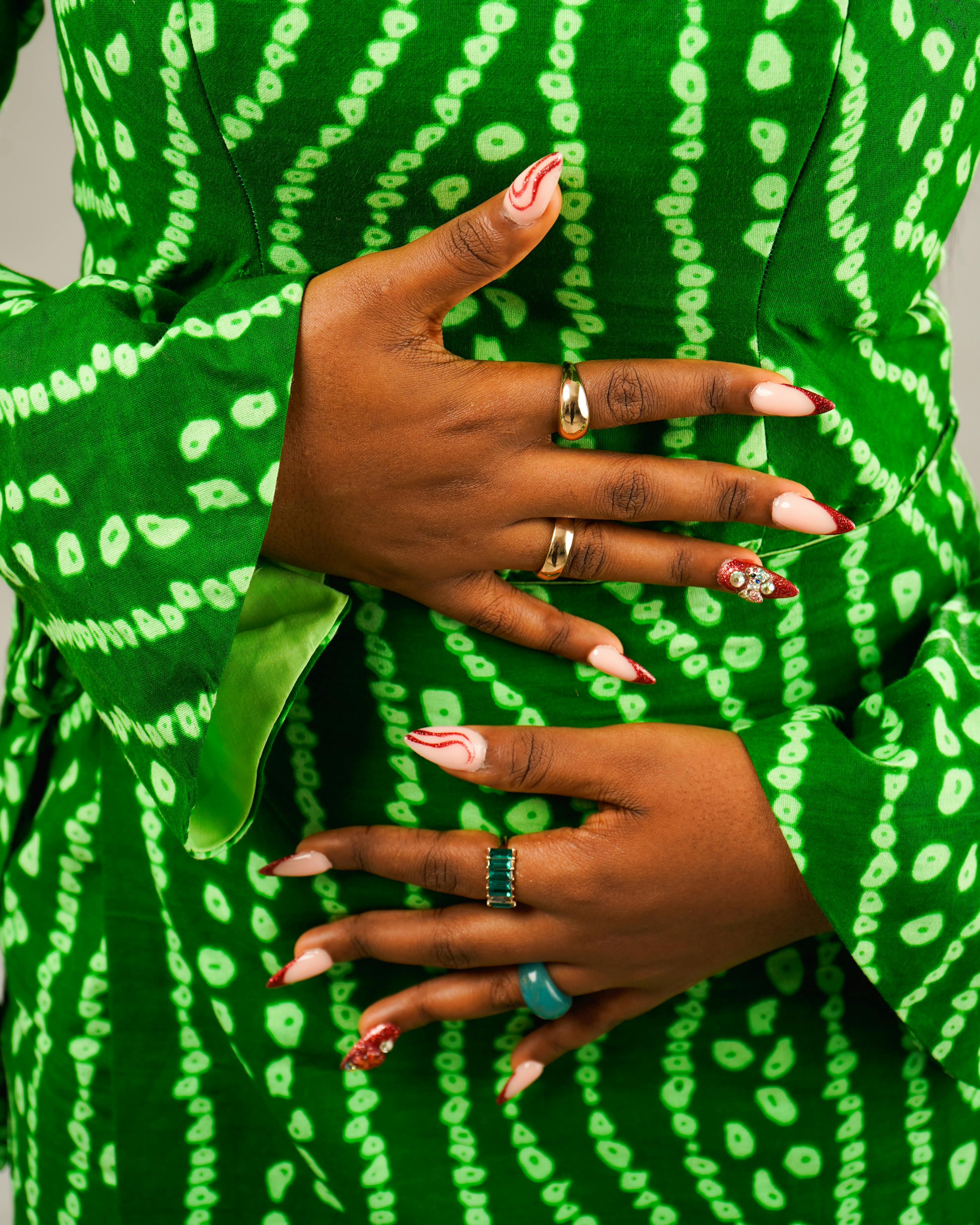 Zadarmo Detailný záber na ruky s zdobenými nechtami v zelených šatách s africkým vzorom a prstene. Fotka z fotobanky