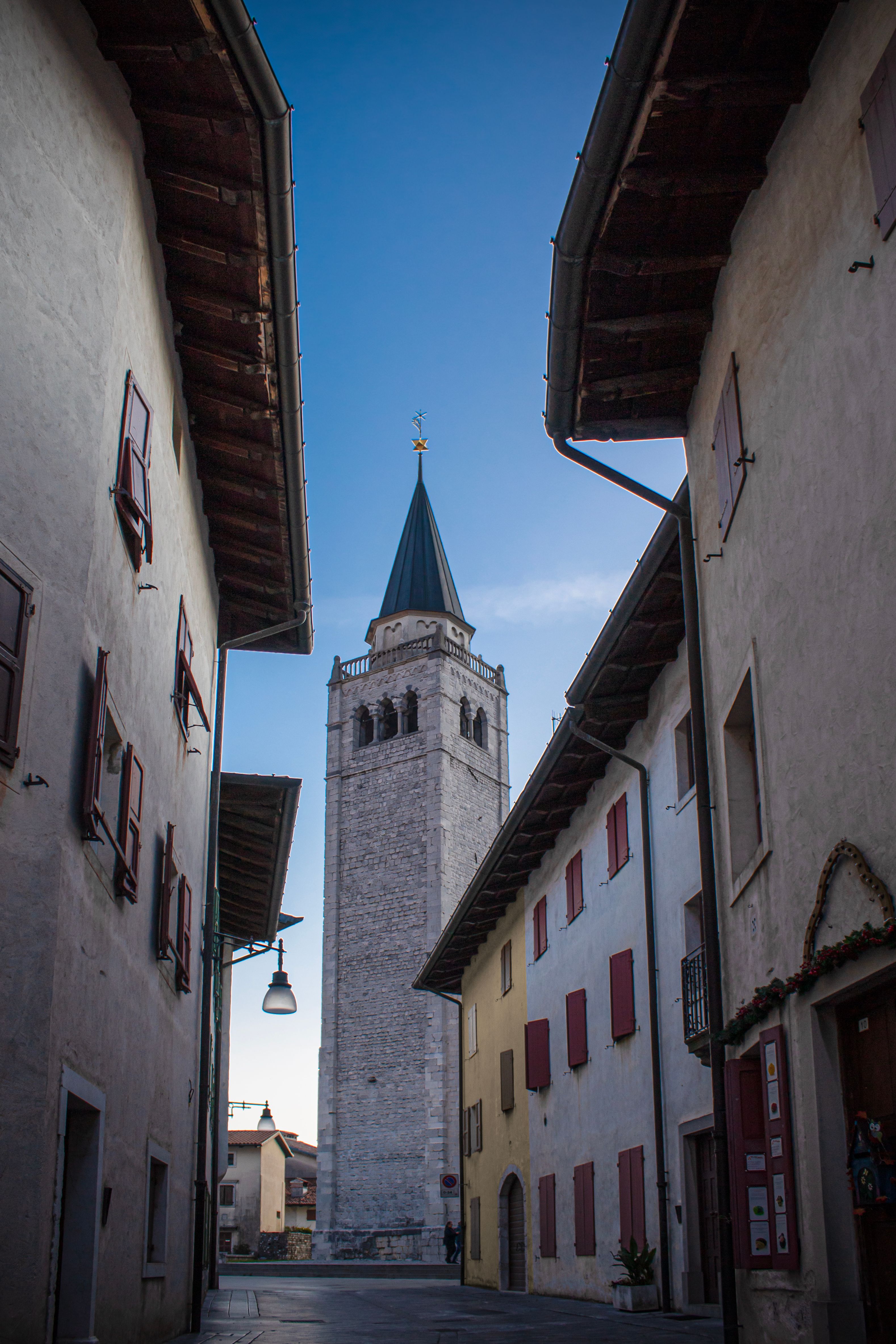 Charming alley view of a historic bell tower in Venzone, Friuli-Venezia Giulia, Italy.