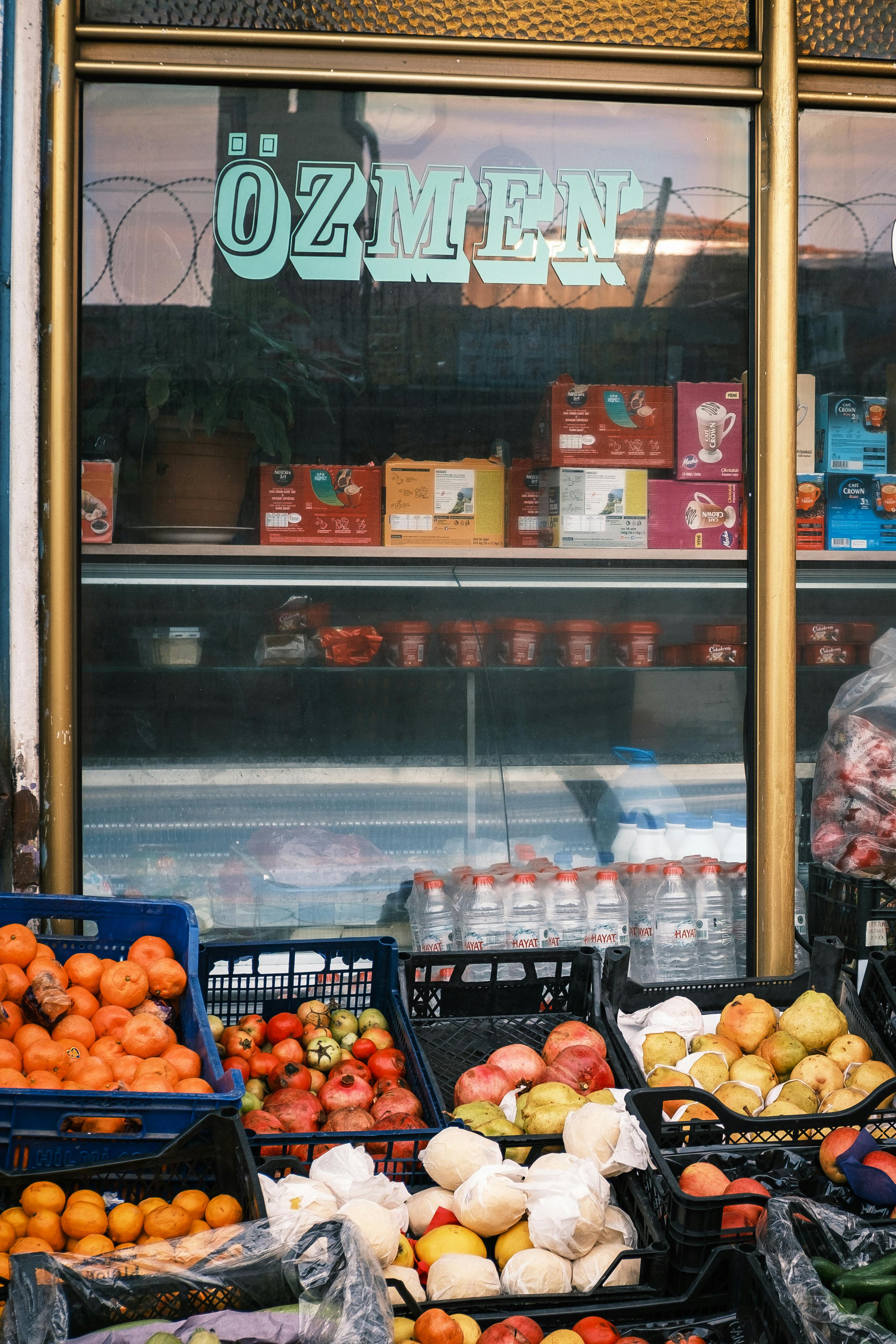 Gratis Livlig utstilling av frukt og varer utenfor en markedsbutikk med skilt. Arkivbilde