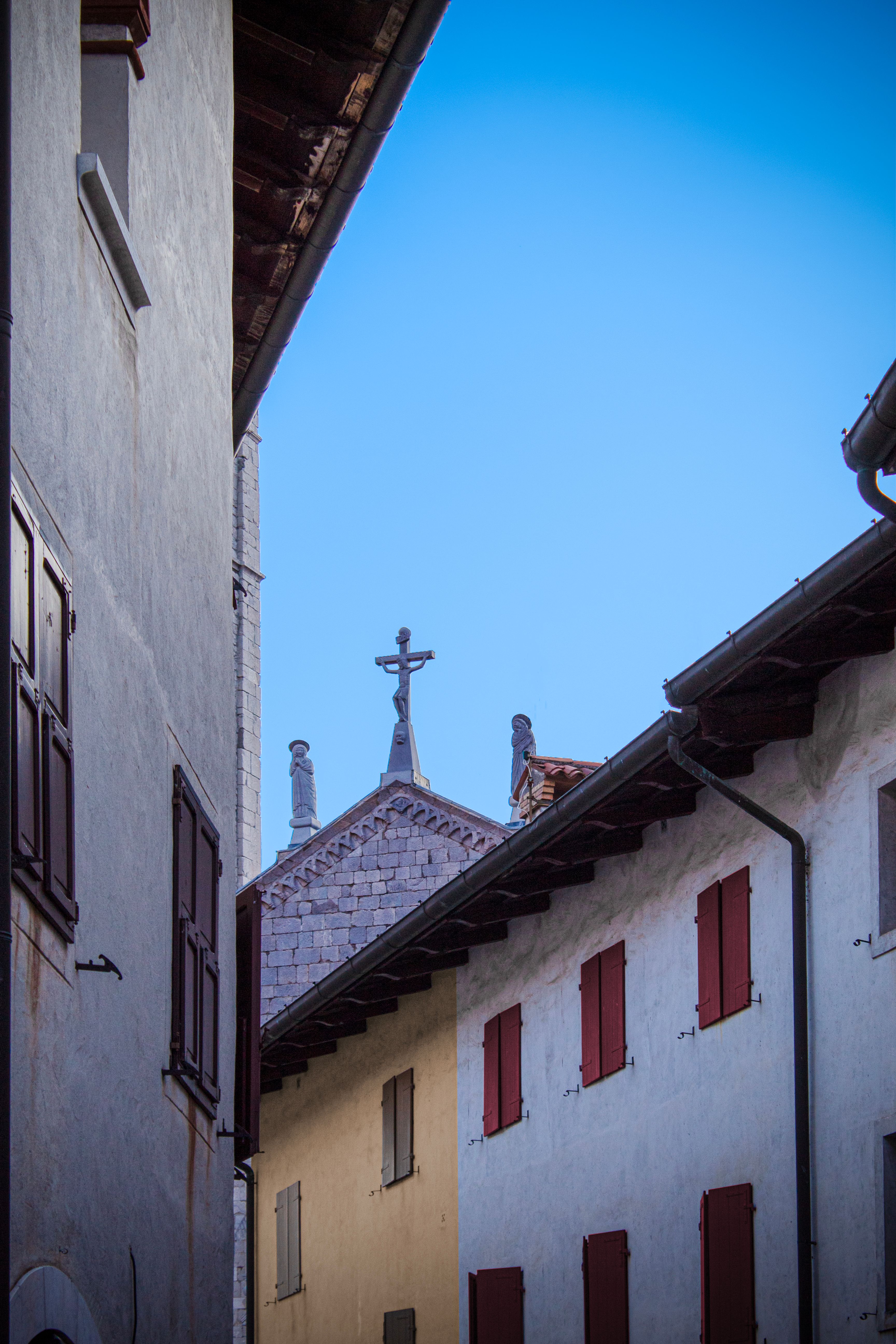 Charming view of architectural beauty in Venzone, Italy with rustic buildings and a church cross.