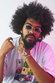 一位留着爆炸头、戴着太阳镜和珠宝的时尚男子，正摆出自信的姿势