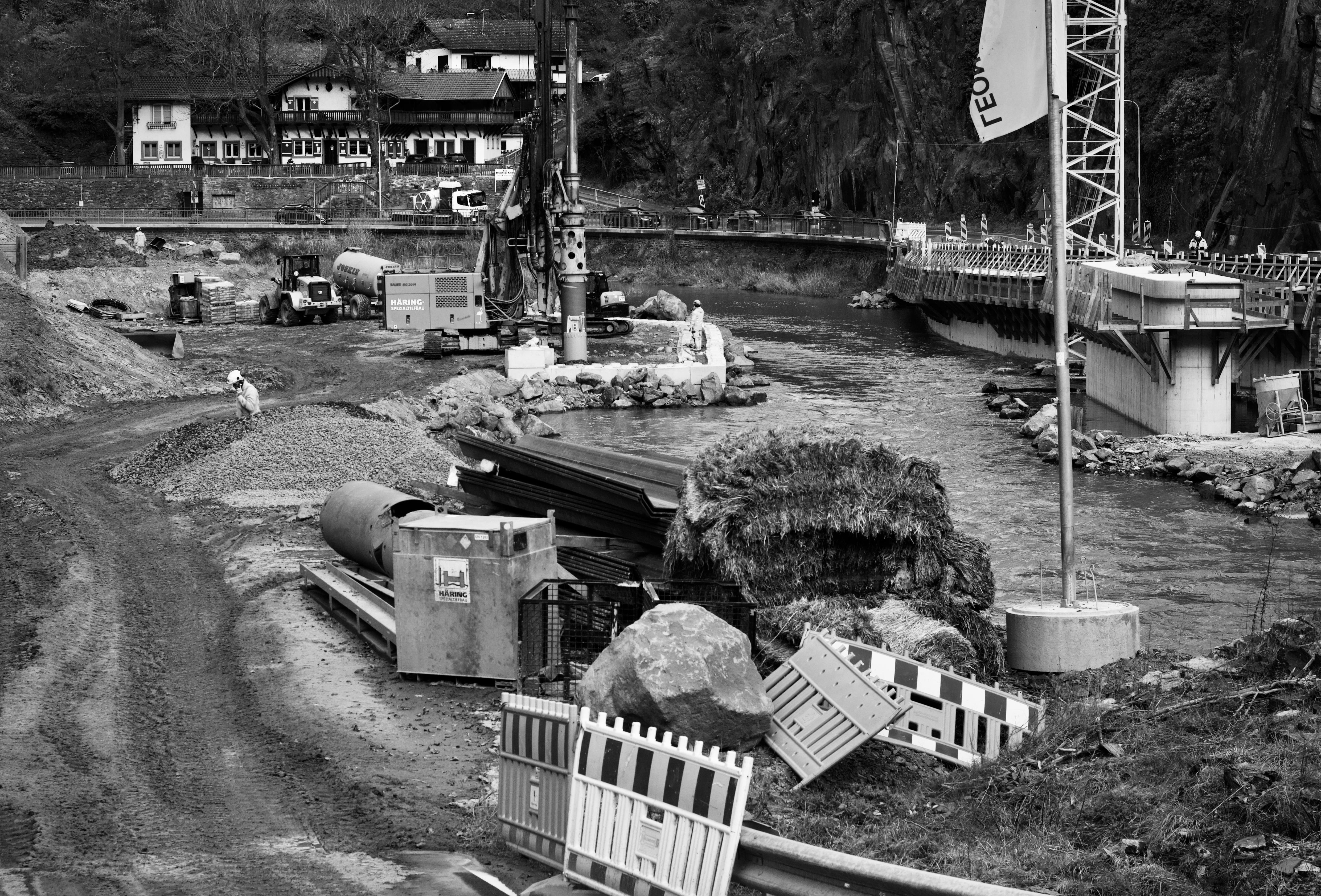 免费 一张黑白照片，拍摄的是河边的建筑工地，有设备和工人。 素材图片