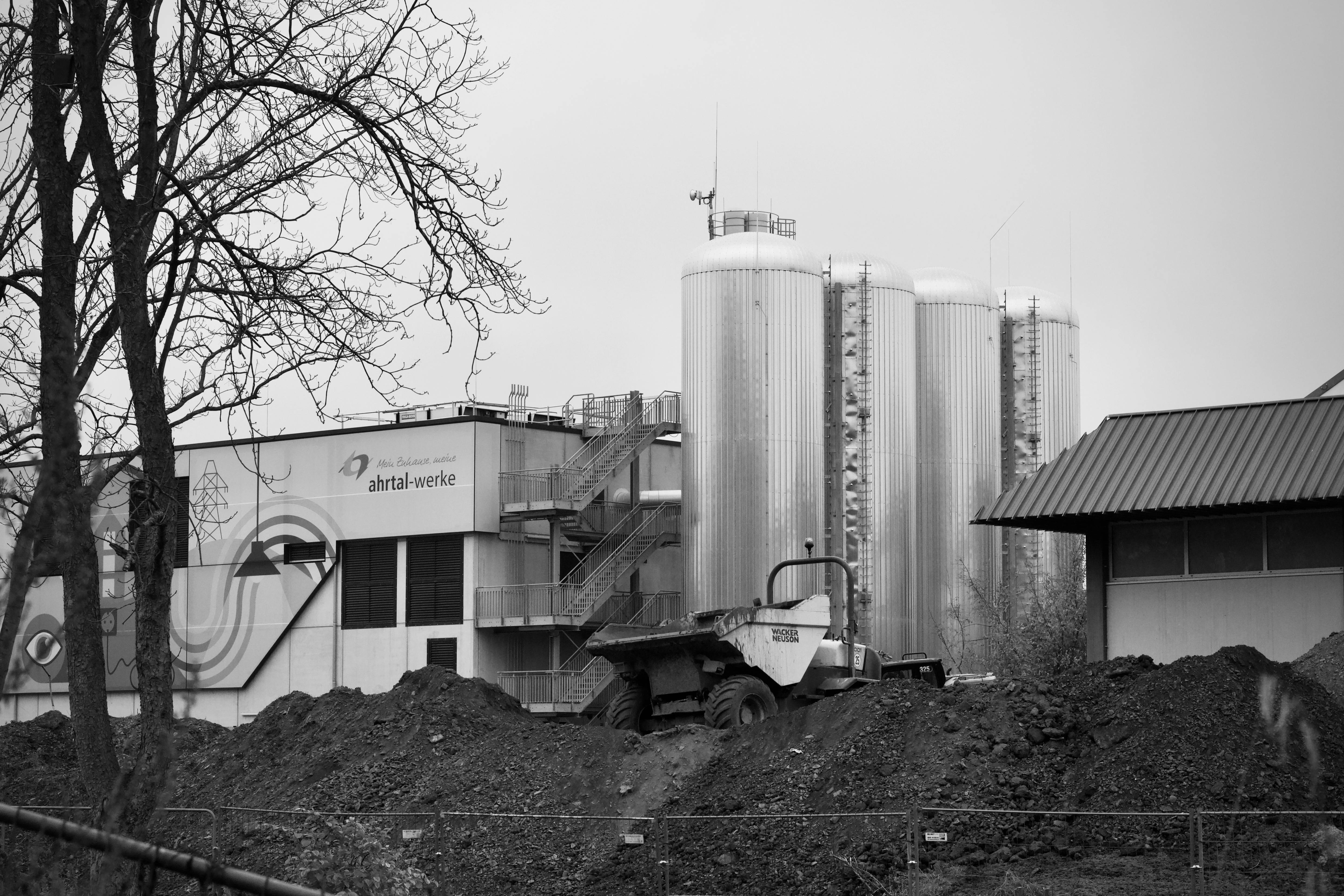 Kostnadsfria Svartvitt foto av en fabrik med silos och en frontlastare på plats. Stock foto