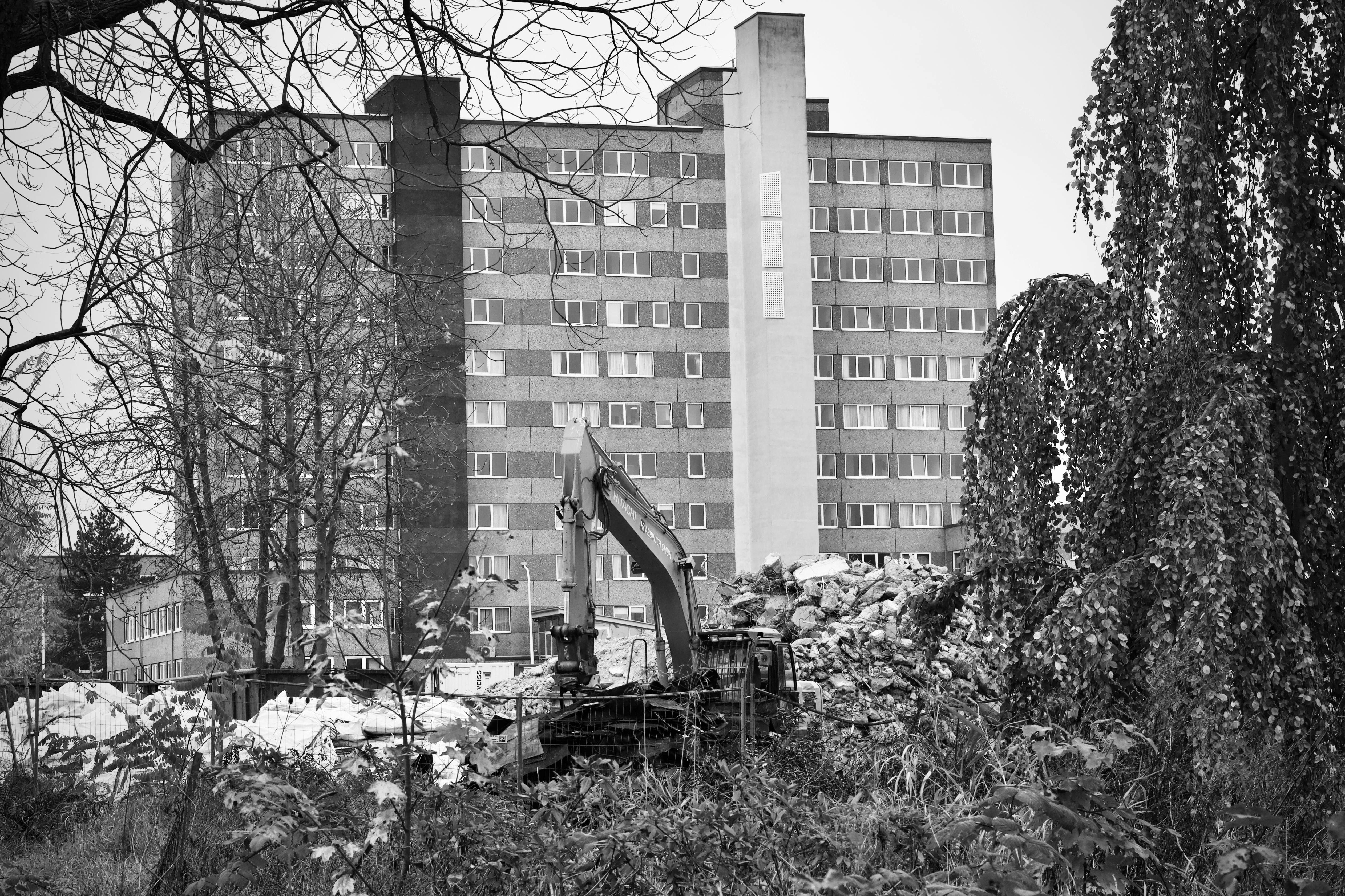 Gratis En gravemaskin blant ruiner foran en høyhus. Arkivbilde