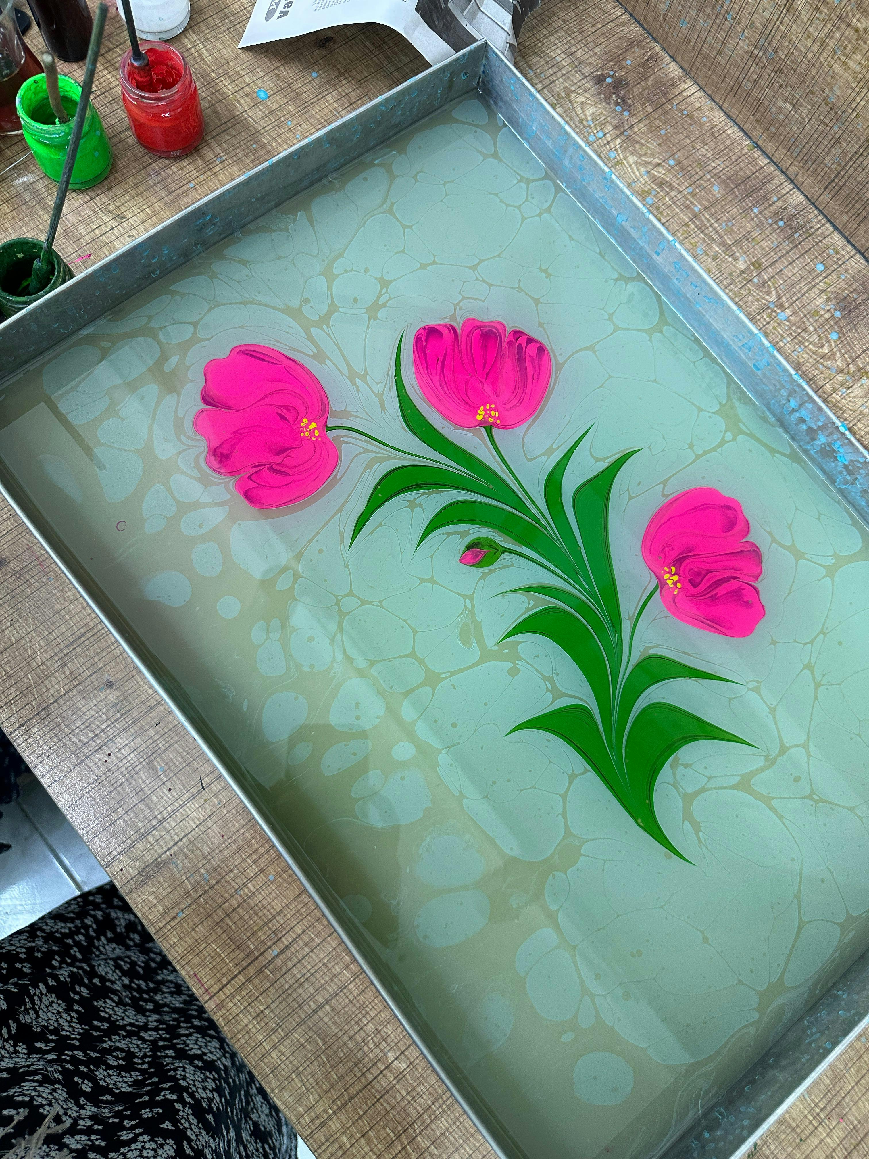 無料 美しいピンクのチューリップをモチーフにした、緑色の絵の具と筆を使ったエブルマーブリングアート。 写真素材