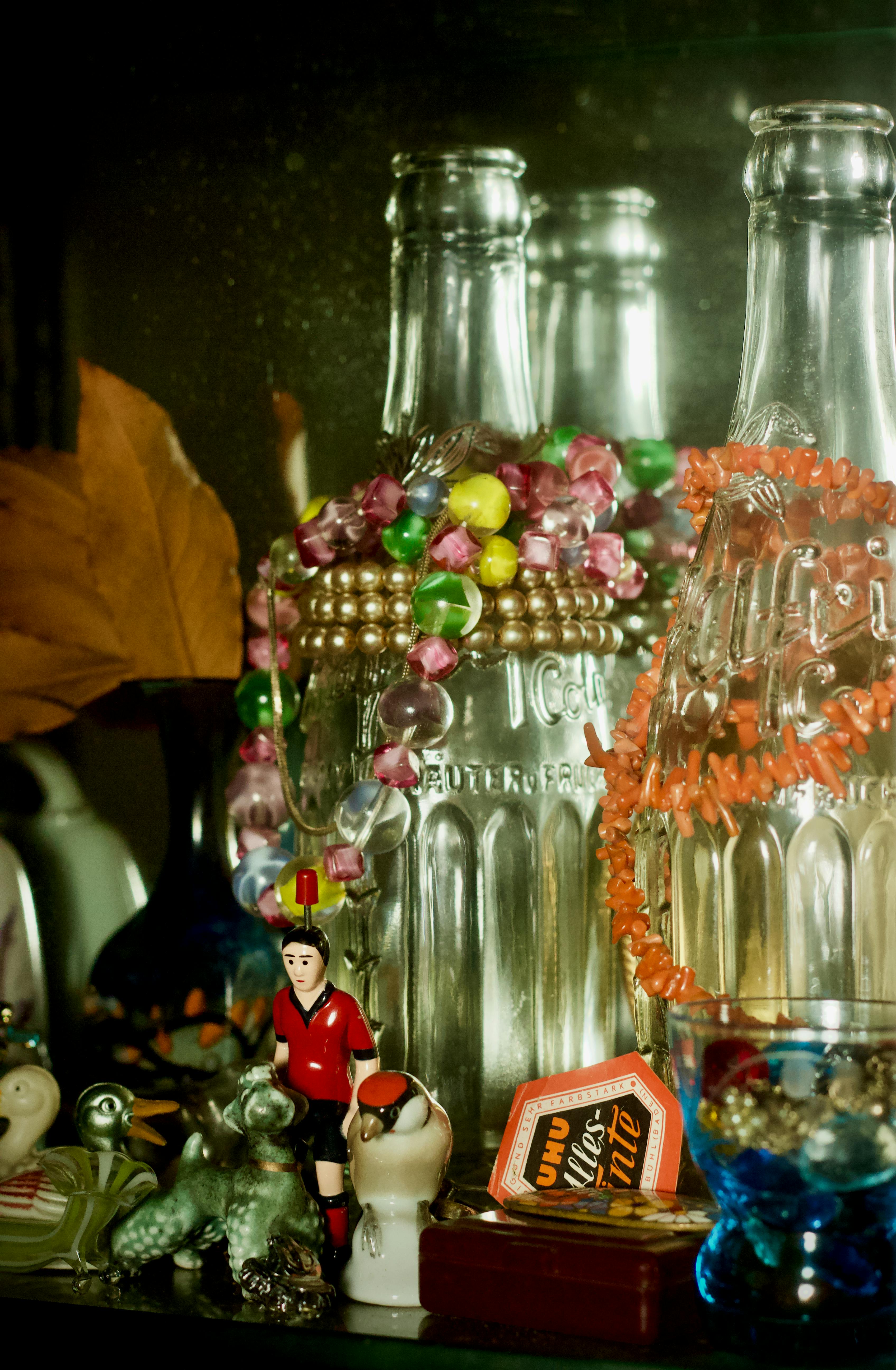 Gratis En dekorativ samling af vintage glasflasker udsmykket med farverige perler og små figurer. Lagerfoto