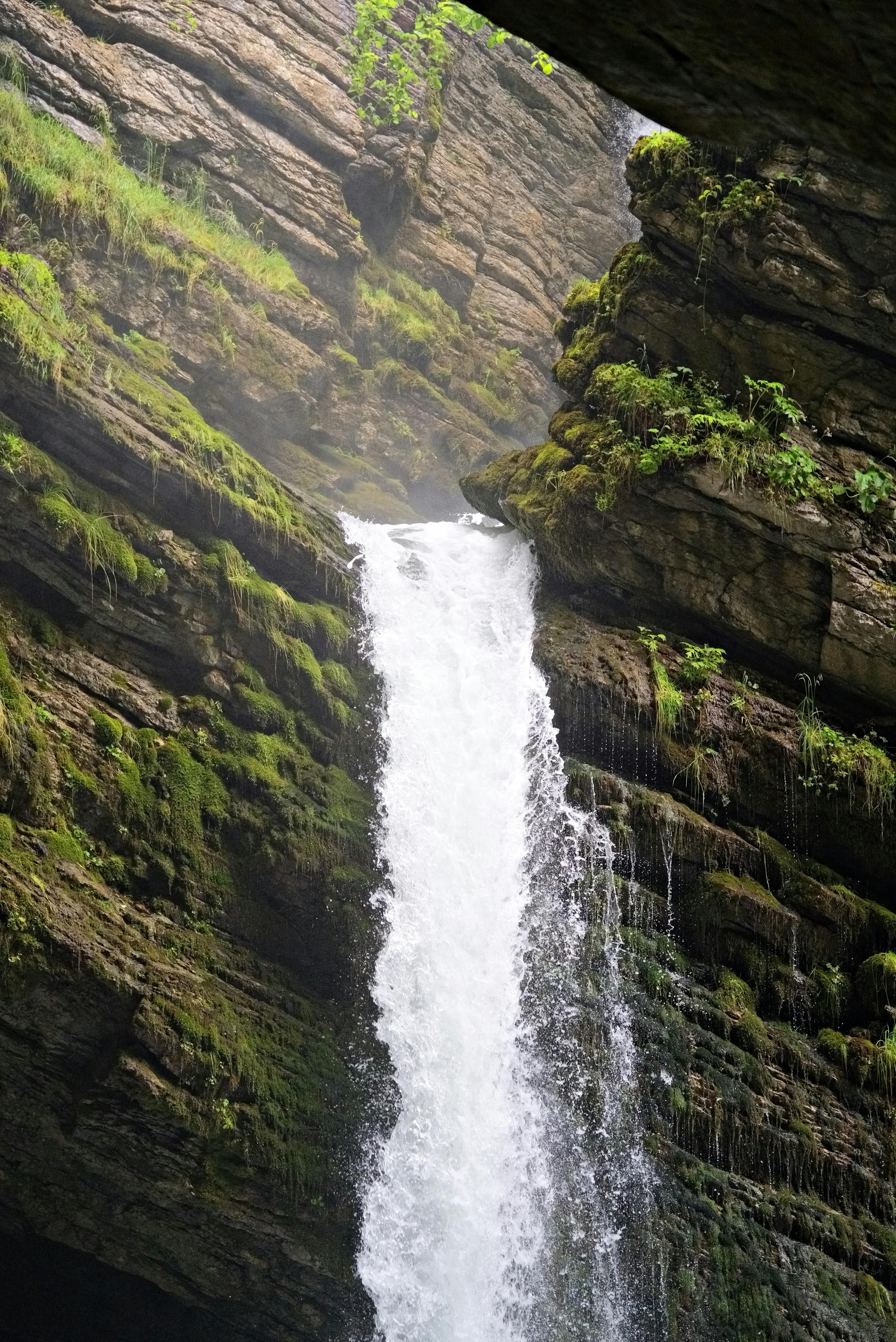grátis Uma bela cachoeira que deságua sobre um penhasco rochoso coberto de musgo, em um cenário natural exuberante. Foto profissional