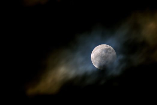 A striking image of the full moon enveloped by ethereal clouds, set against a dark night sky.
