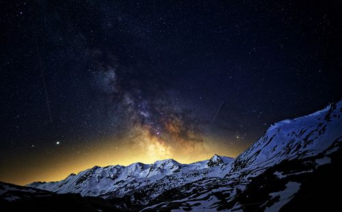 Free The Milky Way illuminates a snowy mountain landscape under a star-filled night sky. Stock Photo