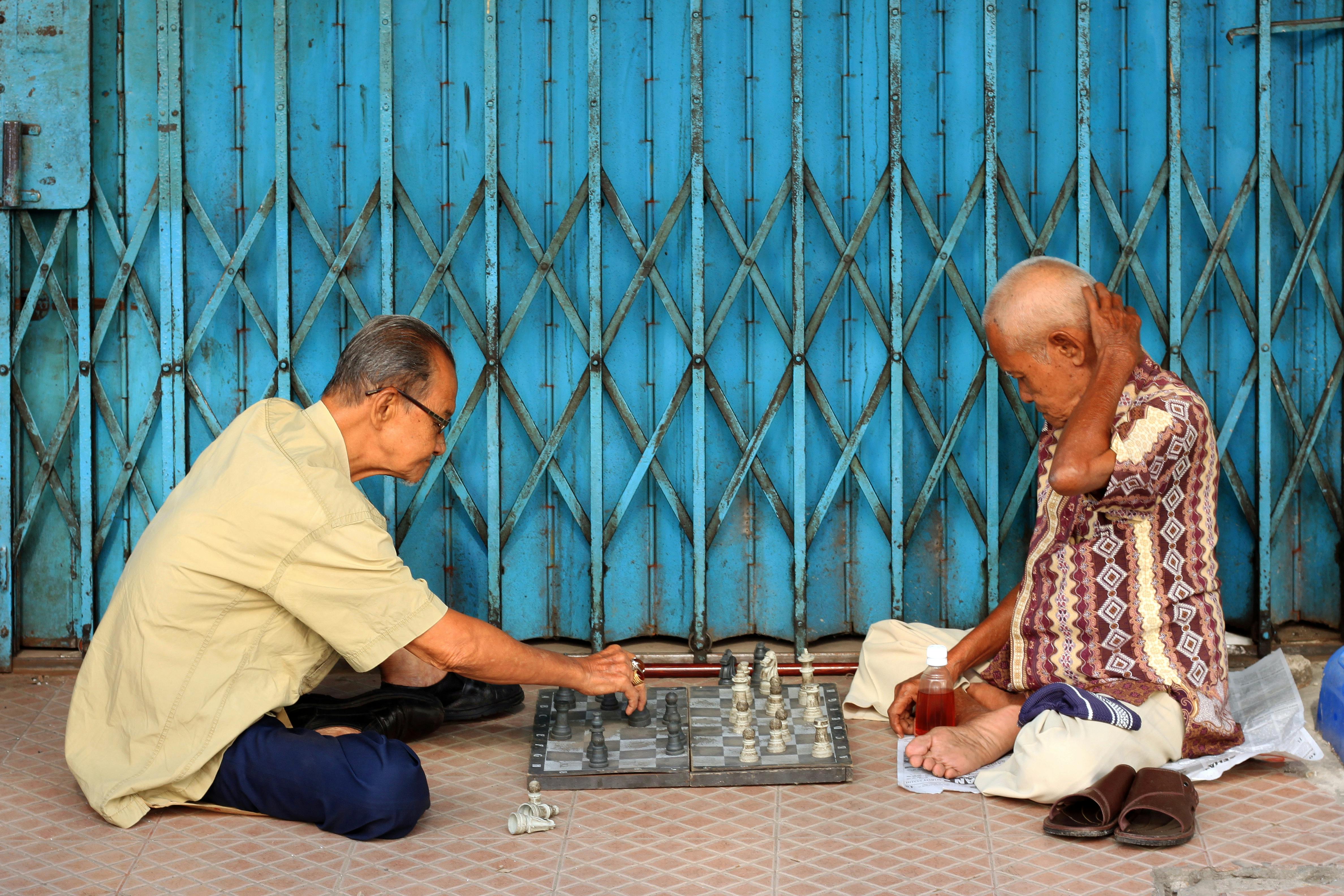 Gratis Due anziani si godono una partita strategica a scacchi per le strade di Jambi, in Indonesia. Foto a disposizione