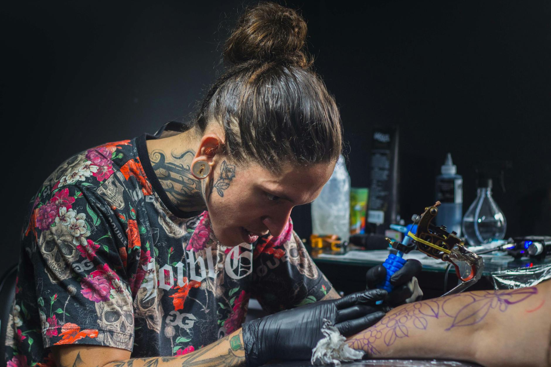 Tattoo artist focusing on creating intricate design in a studio setting.