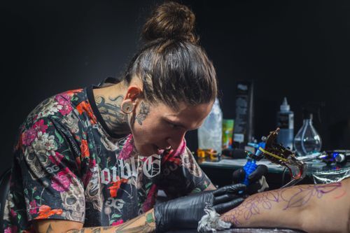 Free Tattoo artist focusing on creating intricate design in a studio setting. Stock Photo