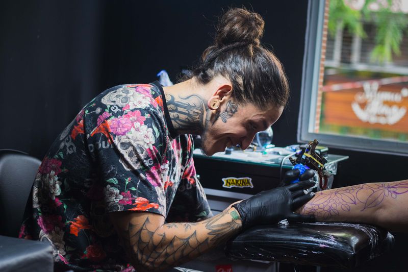 Tattoo artist working on a client's arm