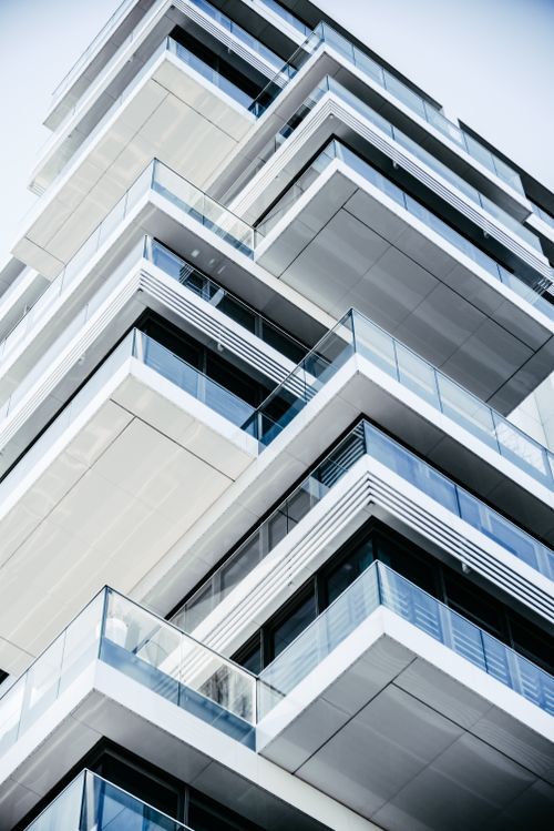 Free Close-up of a contemporary multi-layered building with glass balconies, showcasing modern architecture. Stock Photo