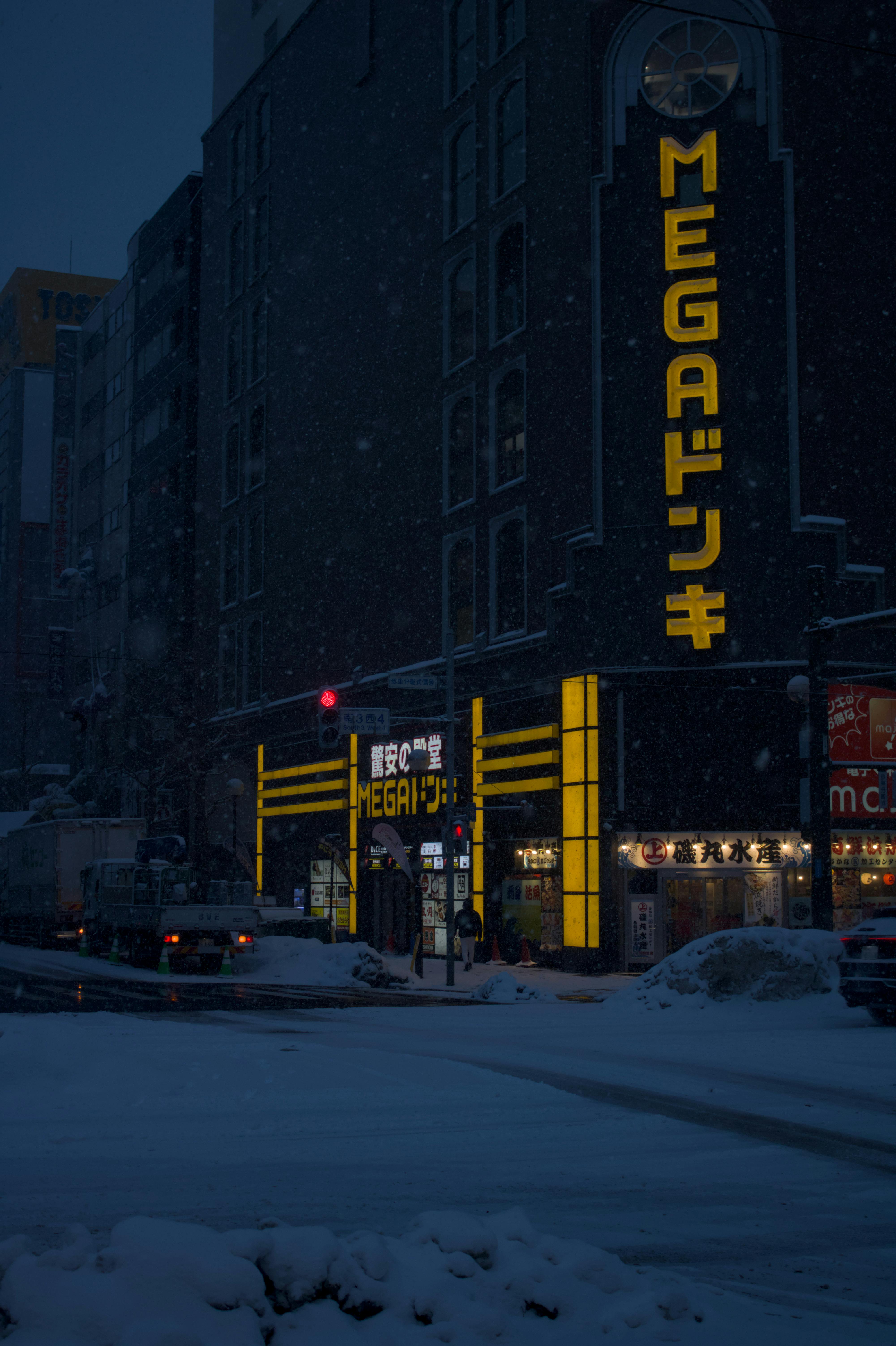 免费 夜晚，日本一家灯火通明的 MEGA 超市外飘落雪花，营造出宁静的都市冬日景象。 素材图片