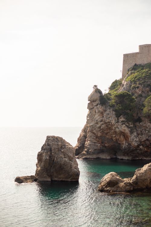 Free A picturesque view of the rocky coast with a historic fort in Dubrovnik, Croatia. Perfect for travel inspiration. Stock Photo