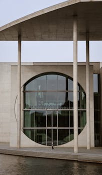 Exterior view of a modern Berlin government building with circular window and walkway.