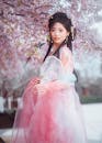 Elegant Woman in Traditional Dress Among Cherry Blossoms