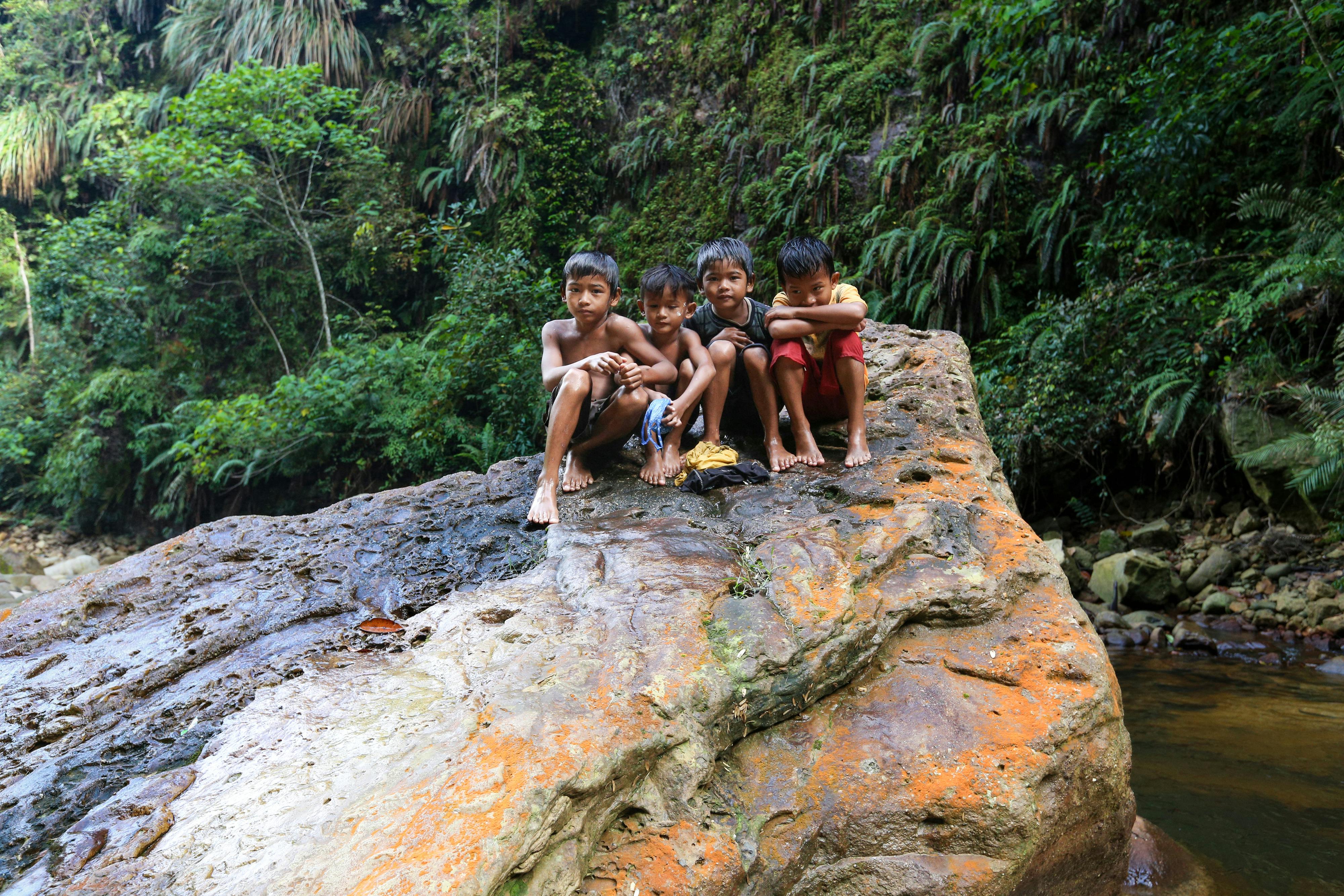 Zadarmo Štyri deti si užívajú čas na skale v bujnej džungli Severnej Sumatry v Indonézii. Fotka z fotobanky