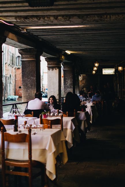 Elegant outdoor dining along a Venice canal with cozy evening ambiance.