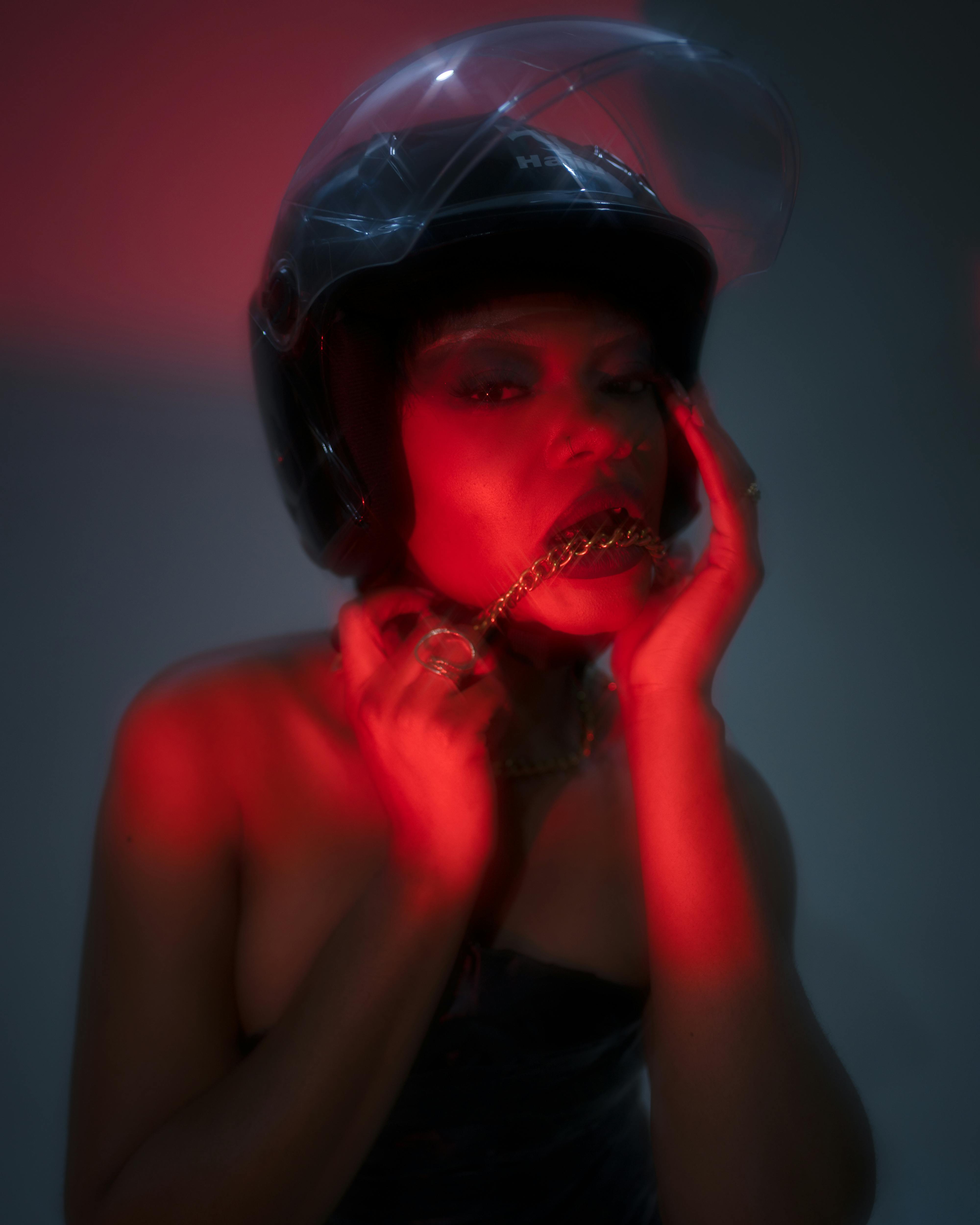 Gratis Retrato artístico de una mujer con casco, iluminación dramática con tonalidades rojas. Foto de stock