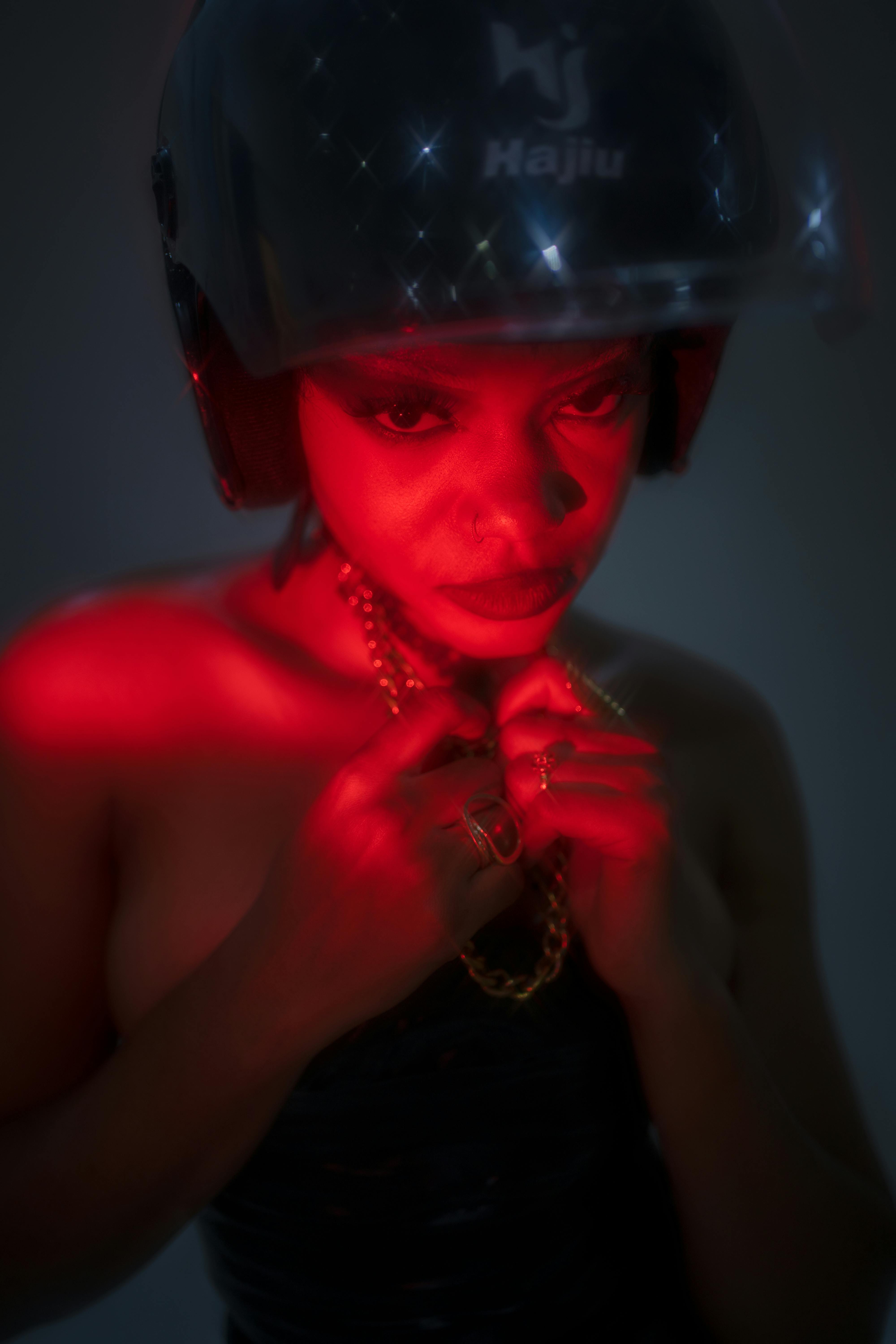 免费 一张引人注目的成年人肖像，他戴着头盔，沐浴在鲜艳的红色灯光中。 素材图片