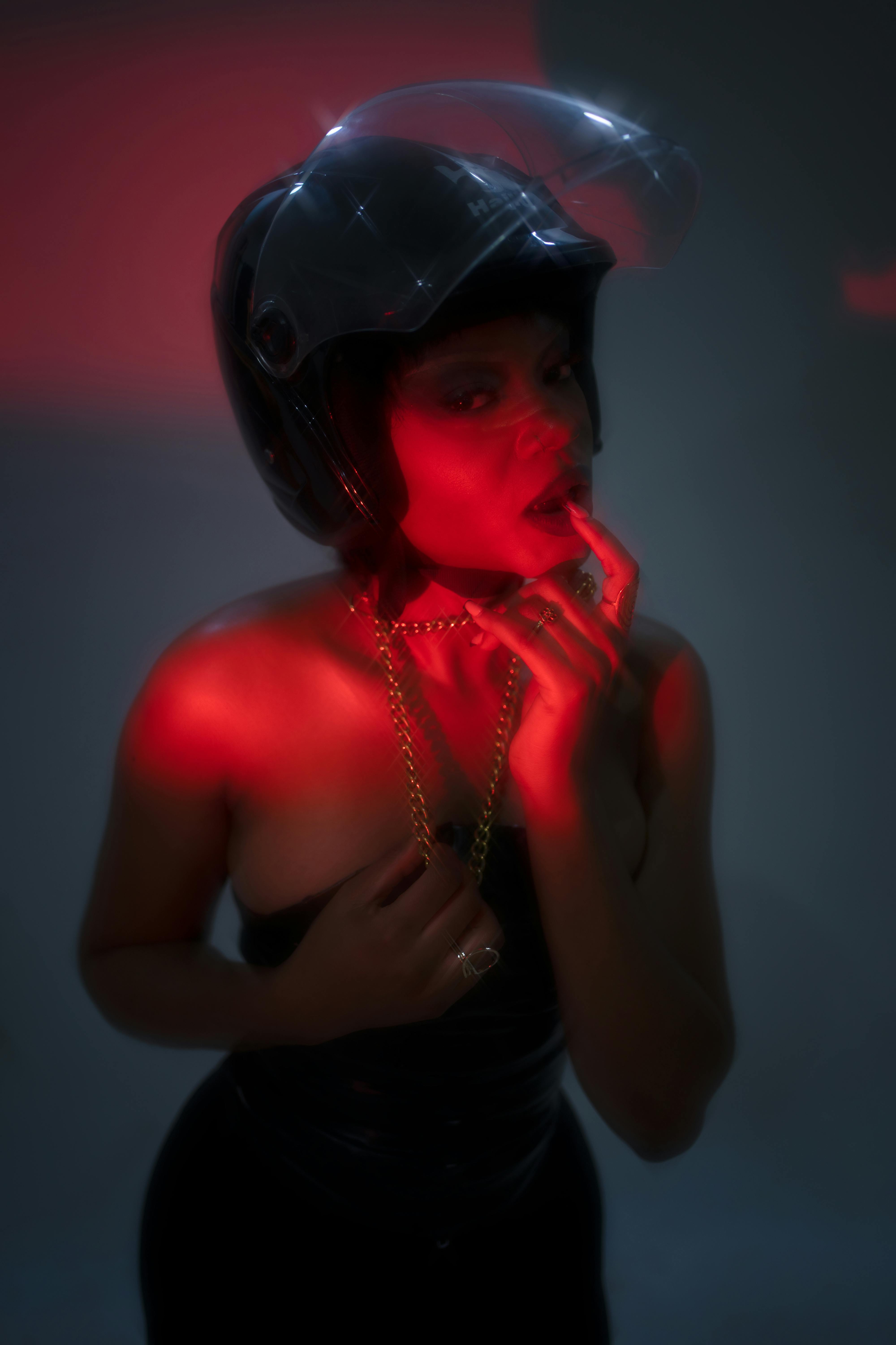 Безкоштовне Драматична студійна фотографія жінки в шоломі з червоним освітленням. стокове фото