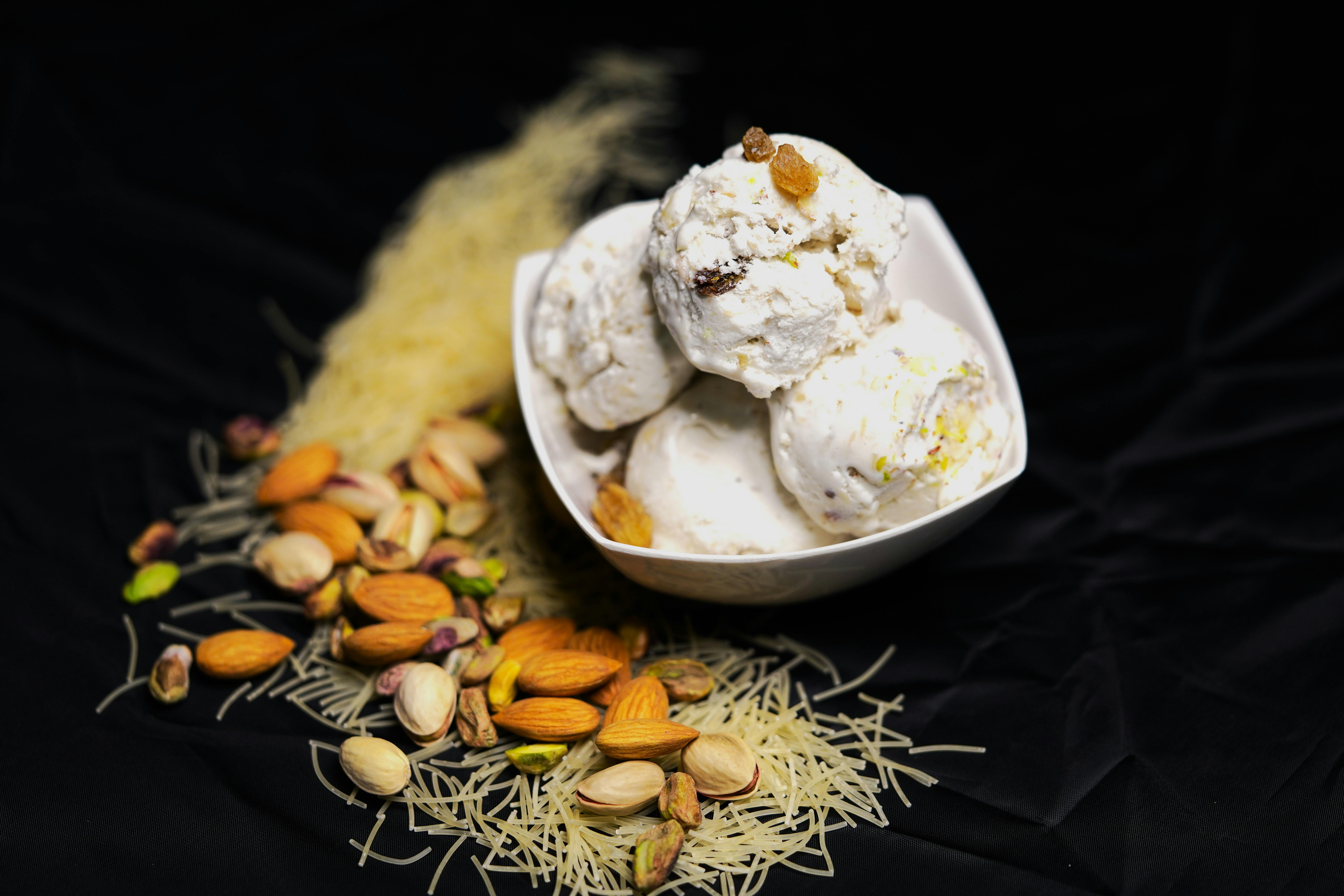 Miễn phí Món kulfi béo ngậy trong bát, điểm xuyết các loại hạt và bún trên nền tối màu. Ảnh lưu trữ