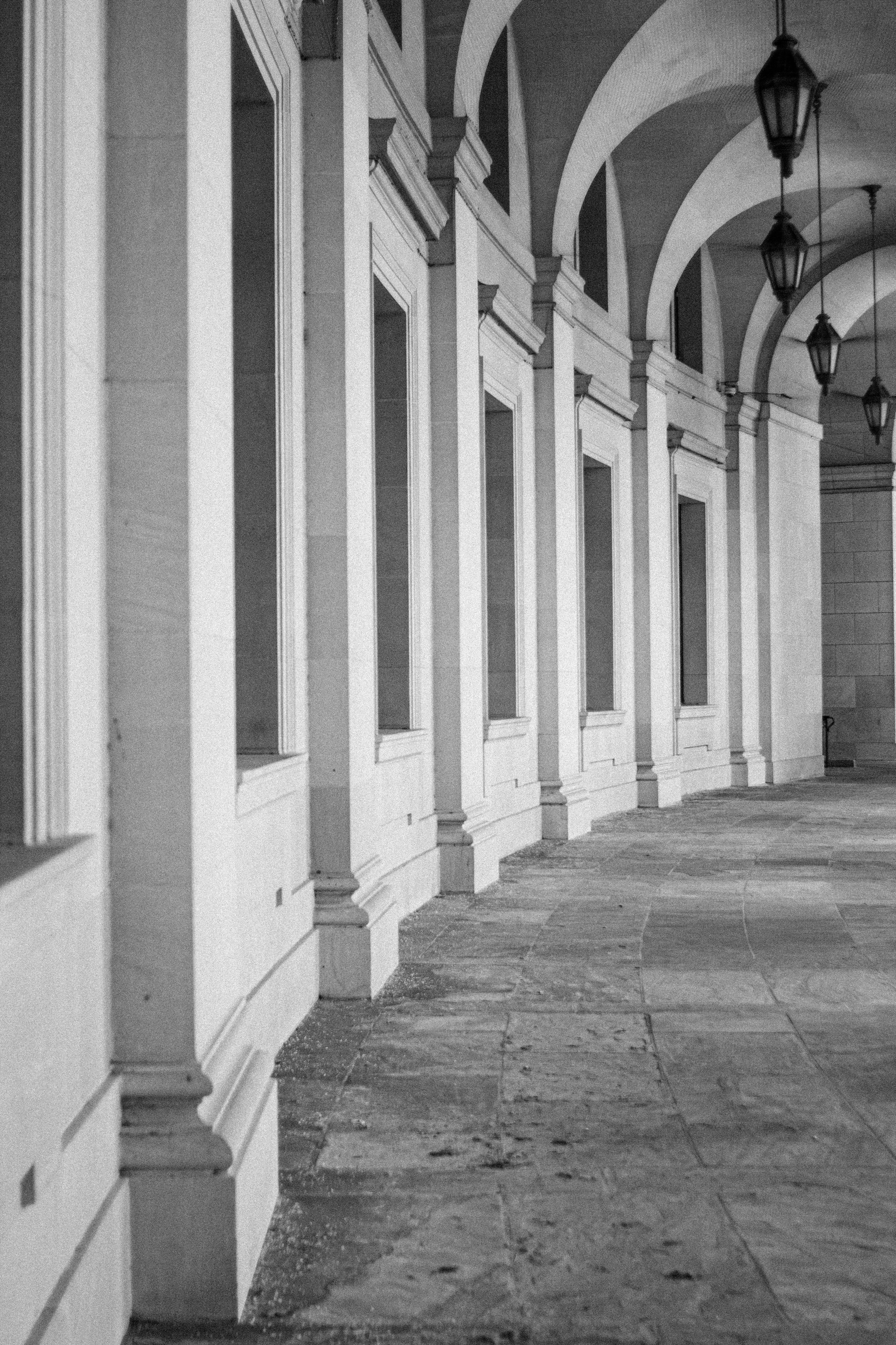 Gratis Sort-hvidt foto af en historisk arkitektonisk korridor med buer og lanterner. Lagerfoto