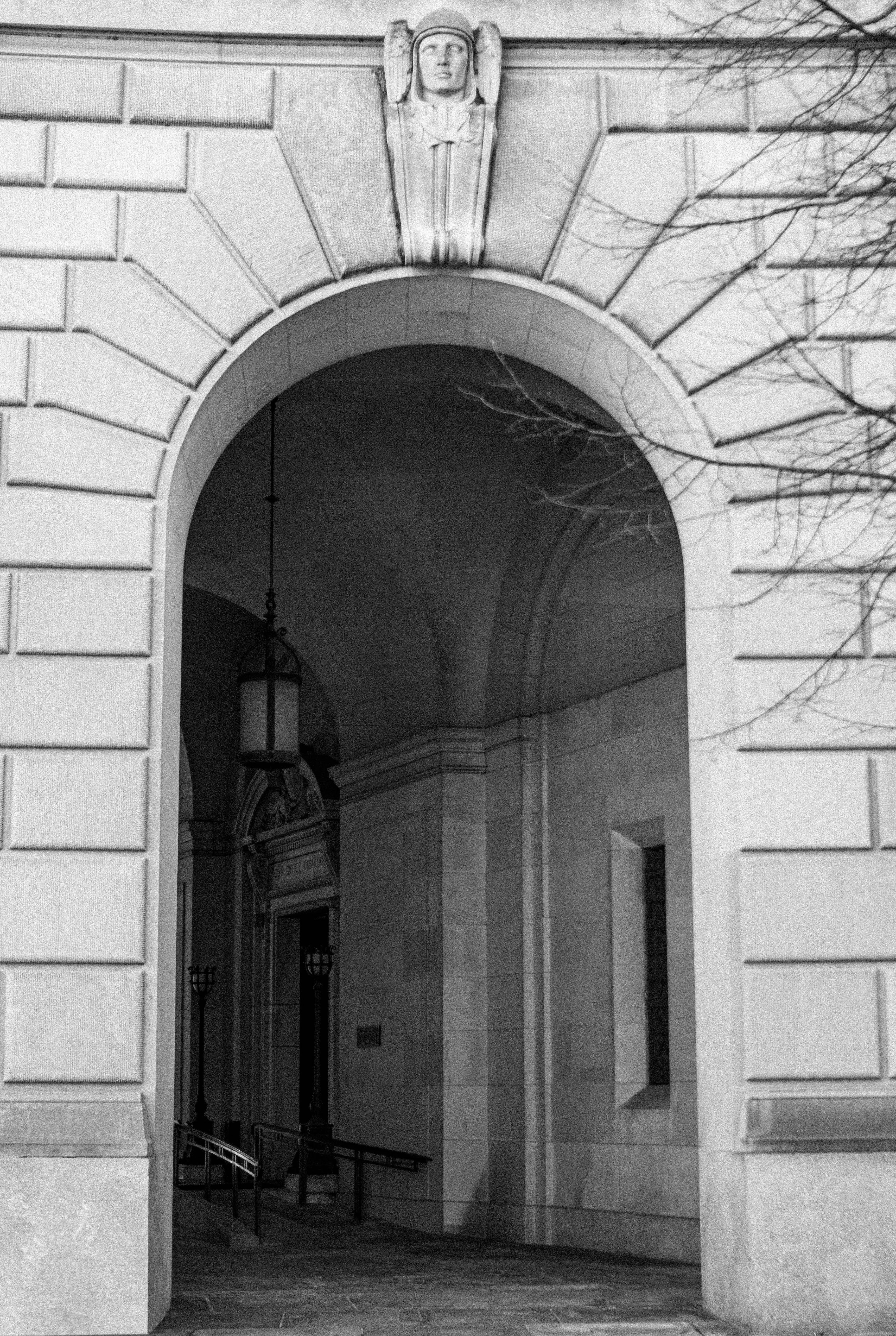 Gratis Sort-hvidt billede af en klassisk stenbuegang med en engleskulptur. Lagerfoto