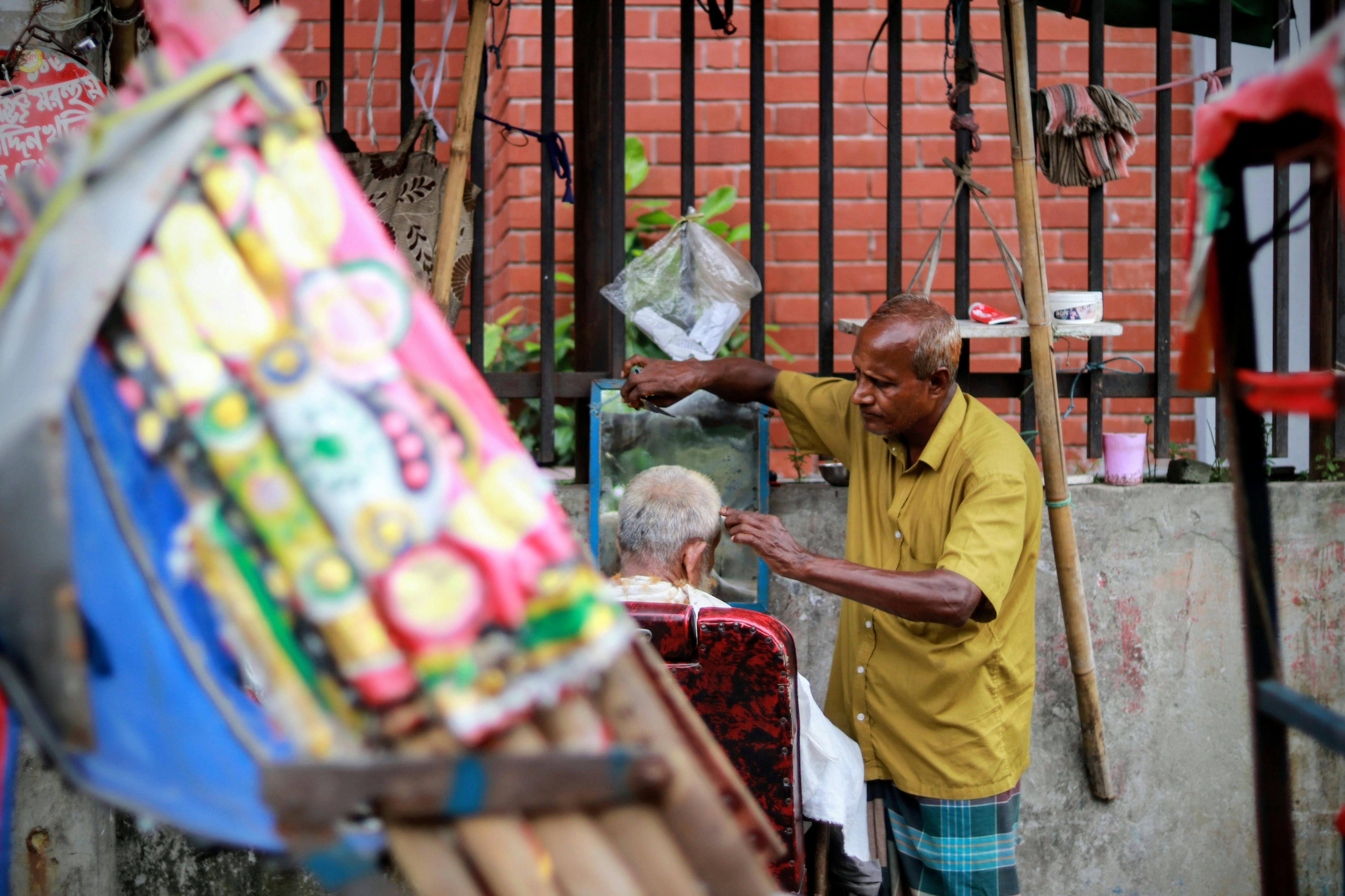 Gratuit Frizerie stradală în aer liber din Dhaka, Bangladesh, care oferă o tunsoare pe o stradă vibrantă a orașului. Fotografie de stoc