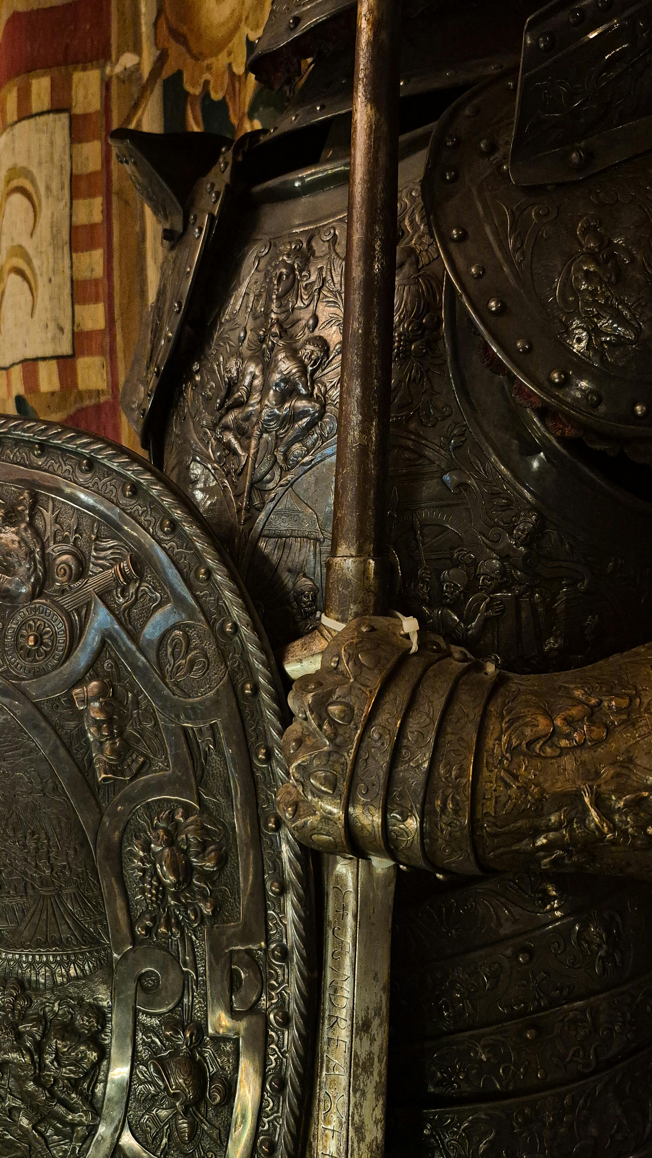 Gratuit Gros plan sur une armure de chevalier médiévale richement ornée de gravures complexes et d'un bouclier, sous un éclairage chaud. Photos