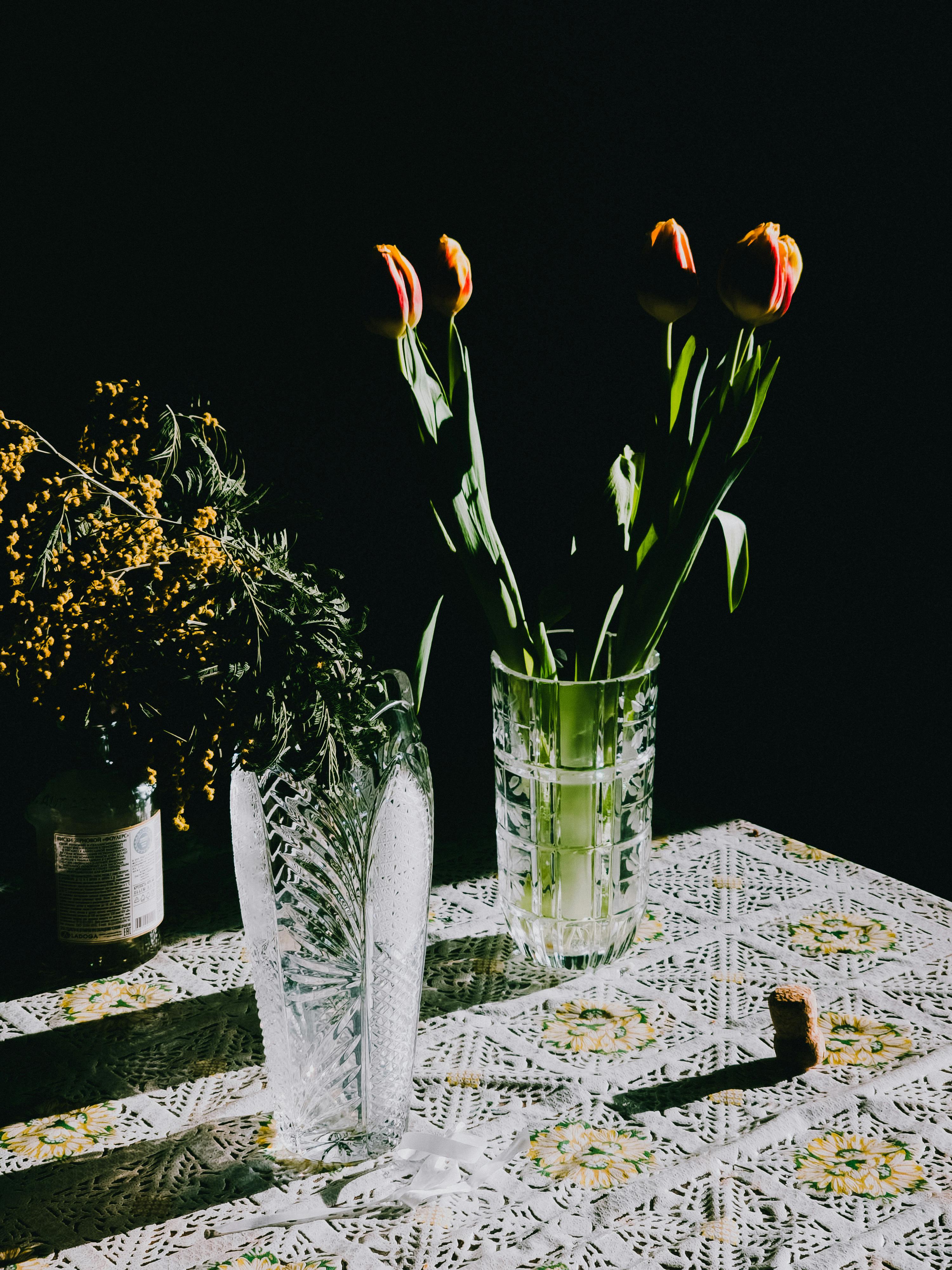 Gratuit O prezentare artistică vibrantă de lalele și mimoze în vaze, pe o față de masă cu model. Fotografie de stoc