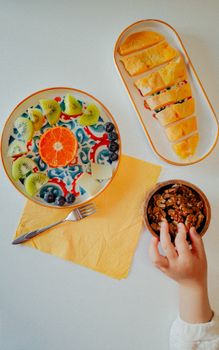 A vibrant breakfast spread with fruits, granola, and yogurt on a bright table setting.