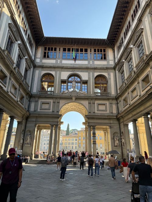 Free People walking through the stunning Uffizi Gallery courtyard in Florence, Italy, under clear skies. Stock Photo