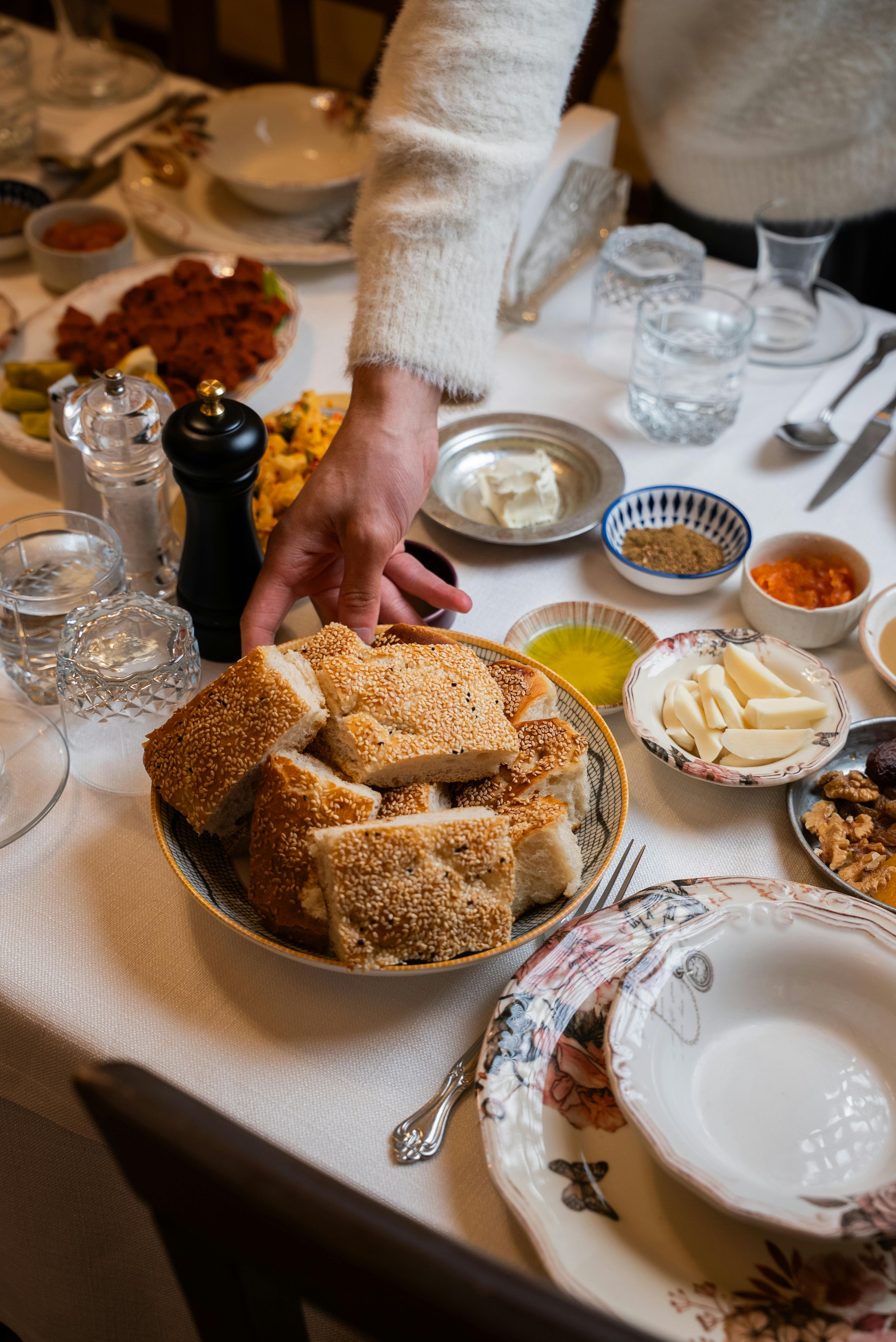 Gratis En traditionel tyrkisk morgenmad med brød, meze og en hånd, der rækker ud efter maden. Lagerfoto