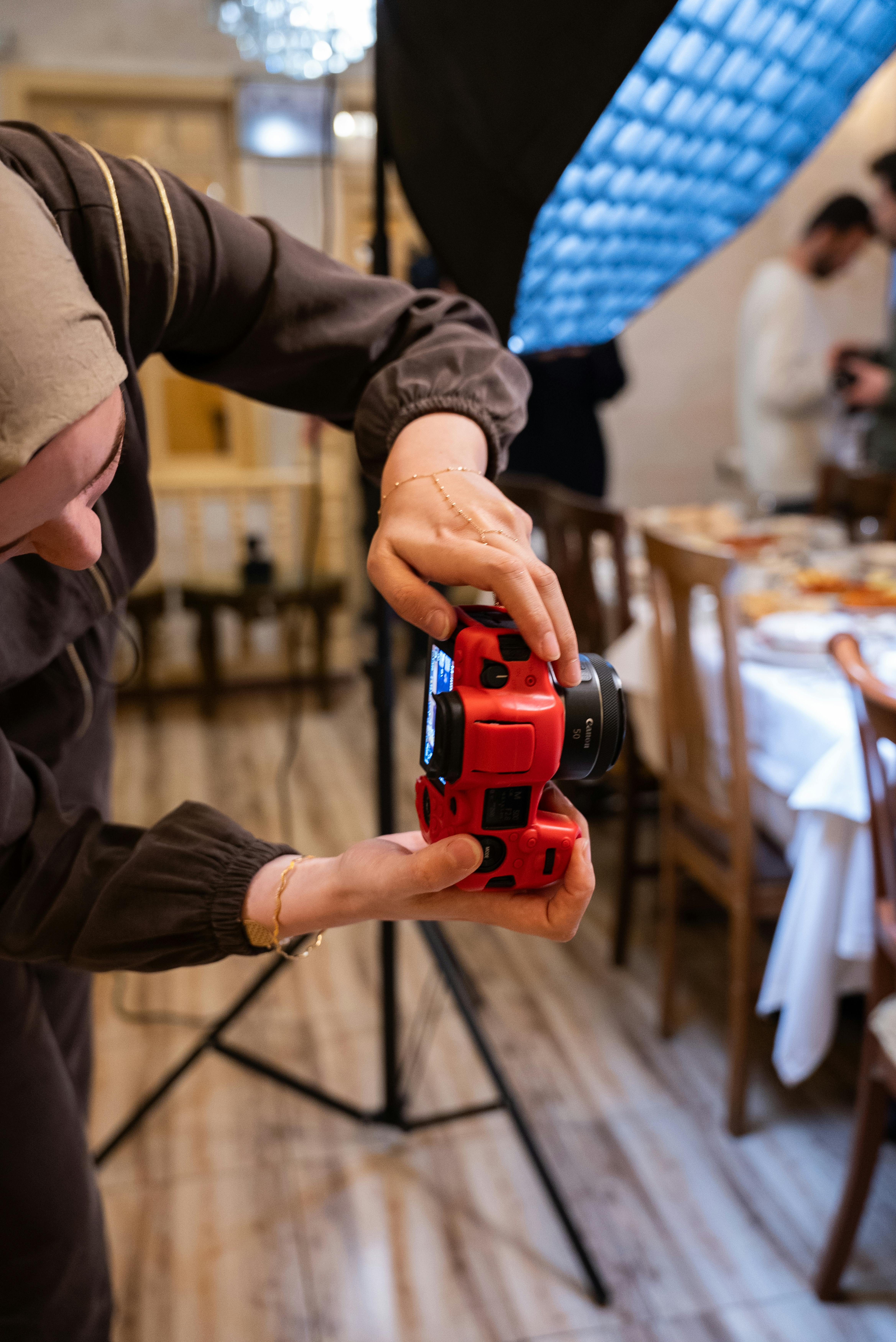 Kostnadsfria Närbild på en fotograf som justerar en kamera under en inomhusevenemangsuppställning. Stock foto